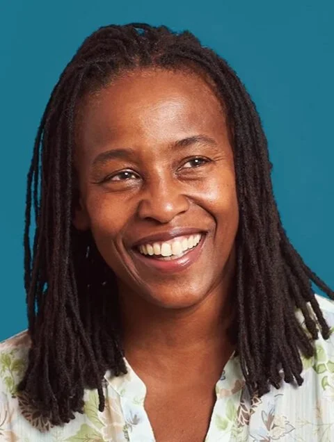 A photo of Stephanie Dinkins, a Black woman with shoulder length hair, a floral bouse, and a smile