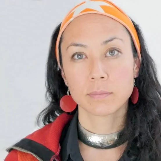 Marissa Jahn has light skin, dark hair, a bandana, dangly earrings, a silver necklace