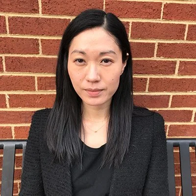 Jenny Rhee has light skin, dark hair, an all black outfit