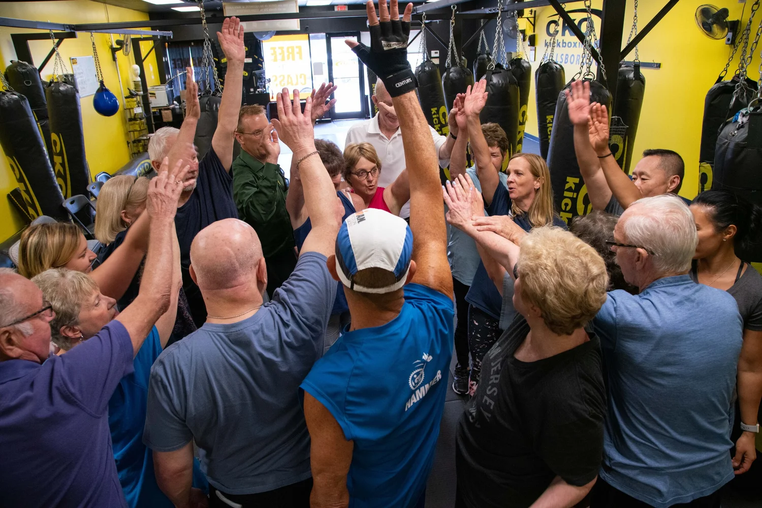 Rock Steady Boxing participants raising their hands together in a group huddle