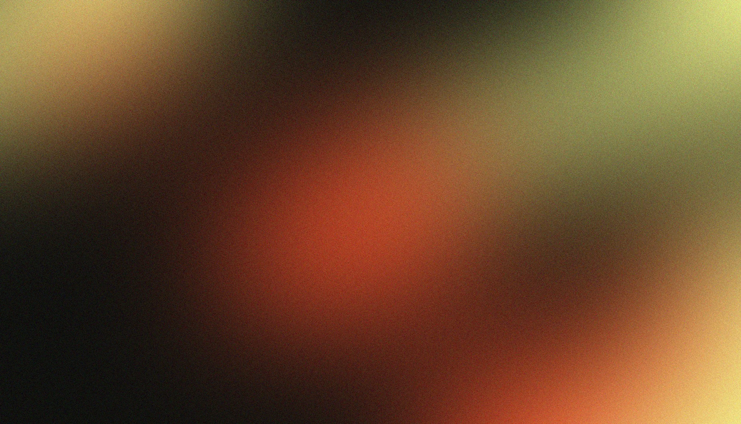A blurred, abstract image with dark, green, red, and black colors, making it difficult to identify specific objects or details.