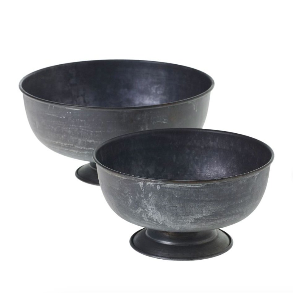 Two black, weathered metal bowls with pedestal bases