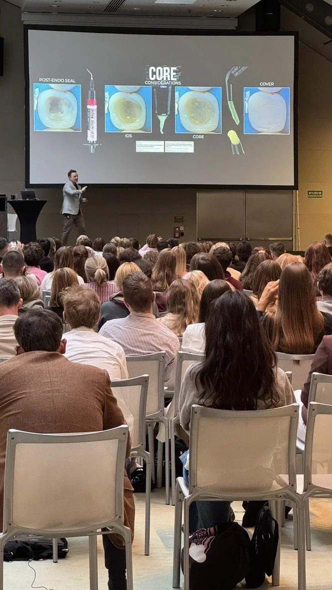 Dentist demonstrating rubber dam isolation during a hands-on dental course, teaching restorative dentistry, matrix systems, and adhesive techniques.