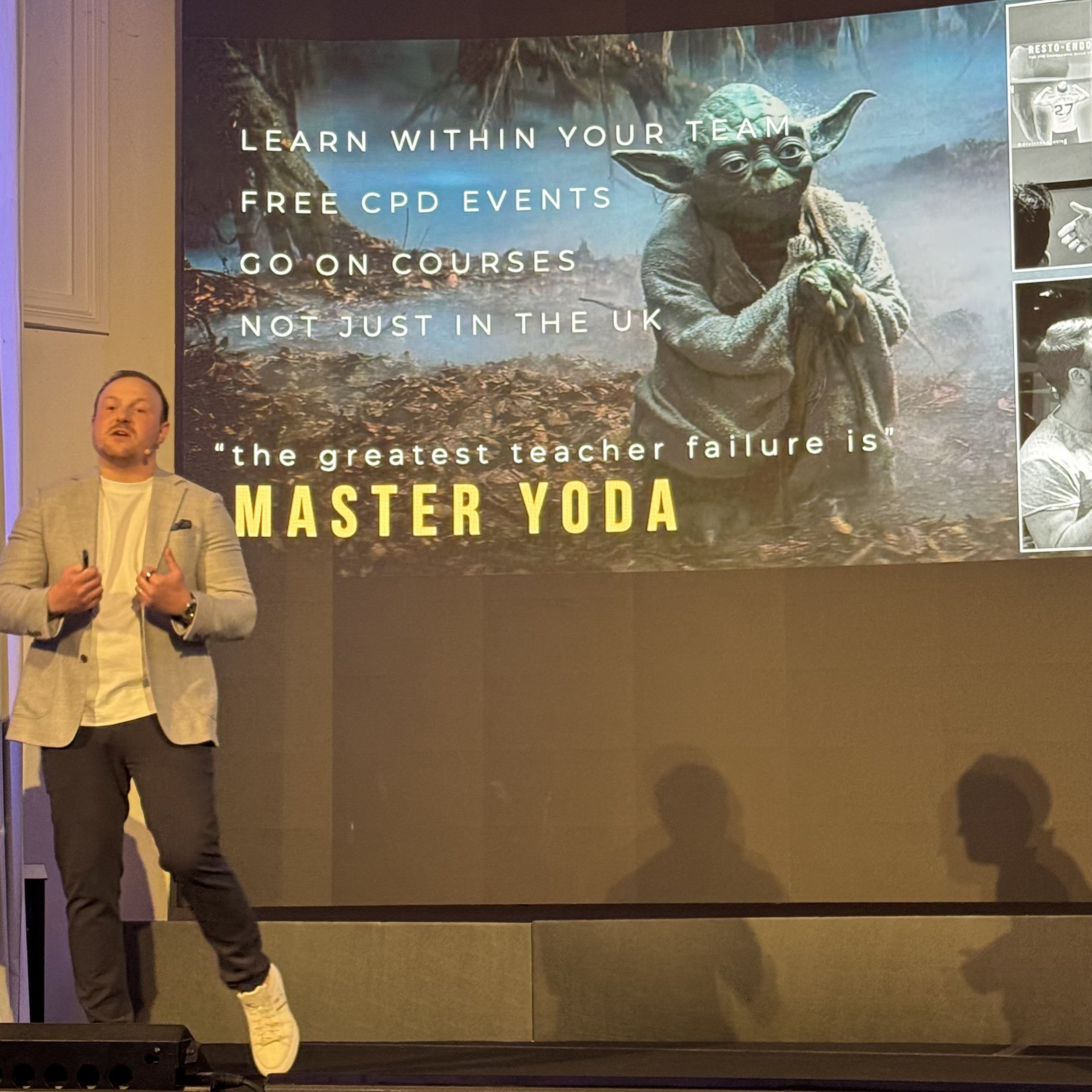 A man giving a presentation on stage with a slide behind him showing Yoda from Star Wars, promoting learning opportunities like free CPD events and courses in the UK. The slide quotes Master Yoda: 'the greatest teacher failure is.'