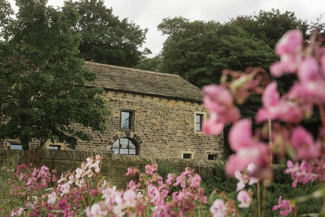  A converted sandstone barn behind pink wildflowers, where the bride got ready near Halifax 