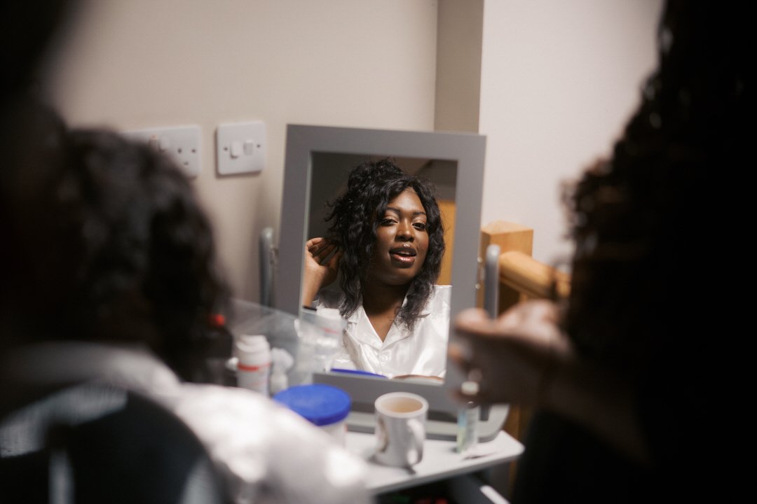  The bride checking her hair in a mirror while getting ready 