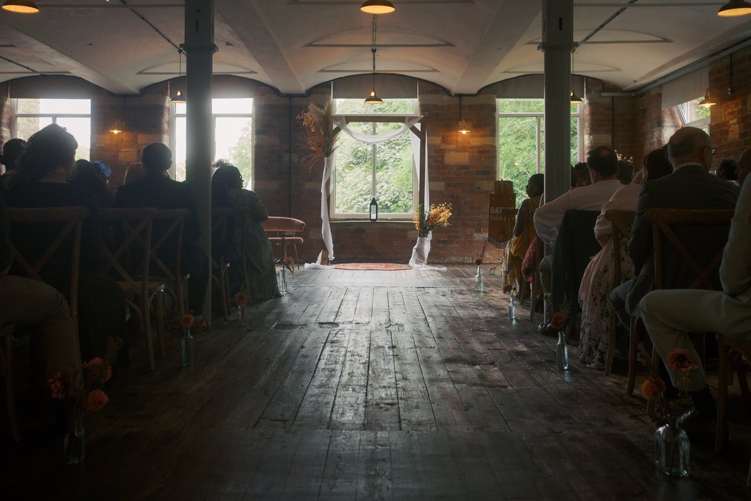  Guests seated either side of the aisle in the brick-walled ceremony room at Bowers Mill 