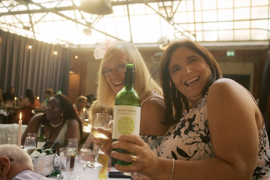  Two guests raising a bottle of wine at the reception at Bowers Mill 