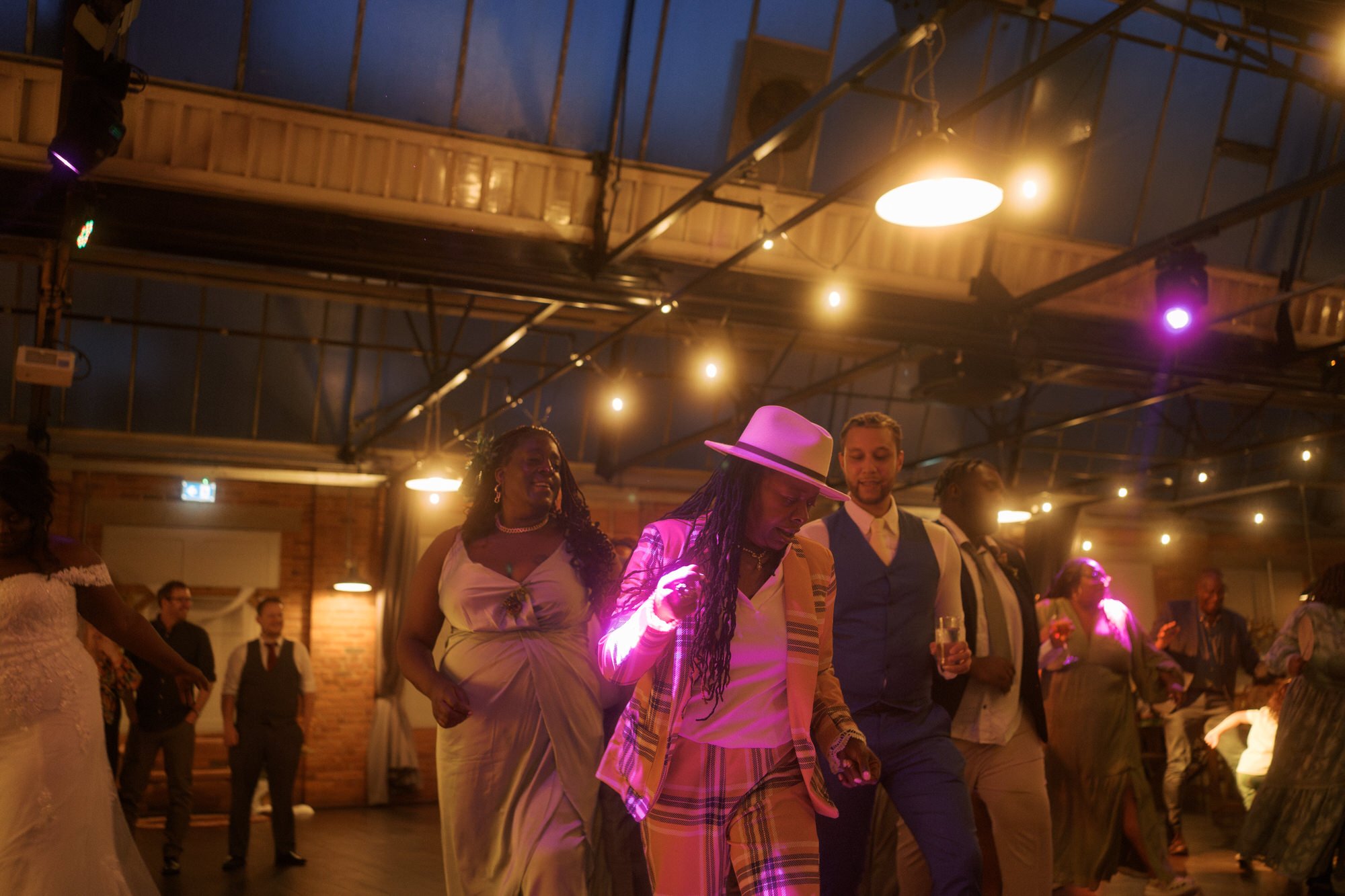  Three guests dancing arm in arm under festoon lights at Bowers Mill 