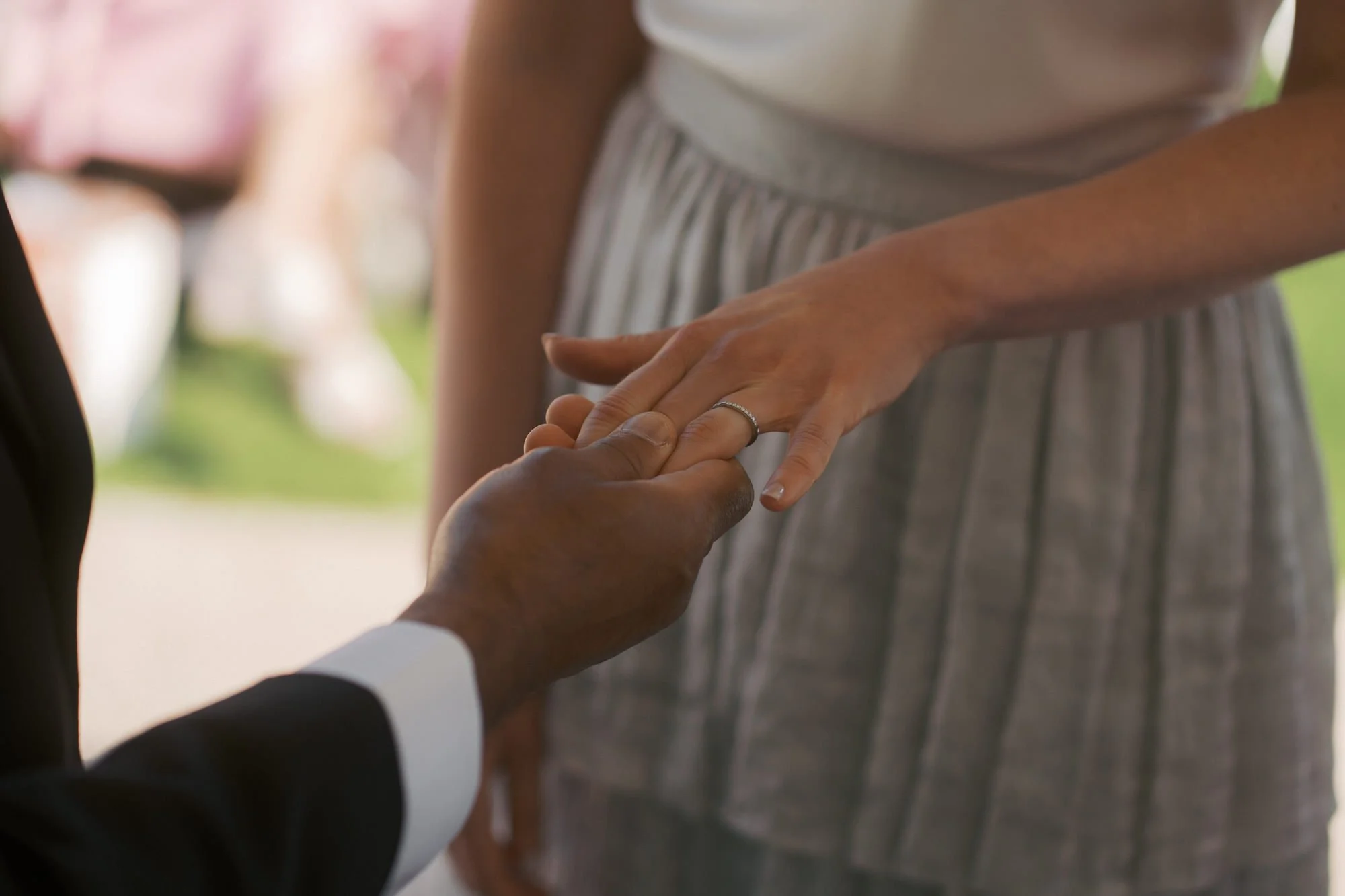  A groom's hand holding a bride's hand as the ring goes on 