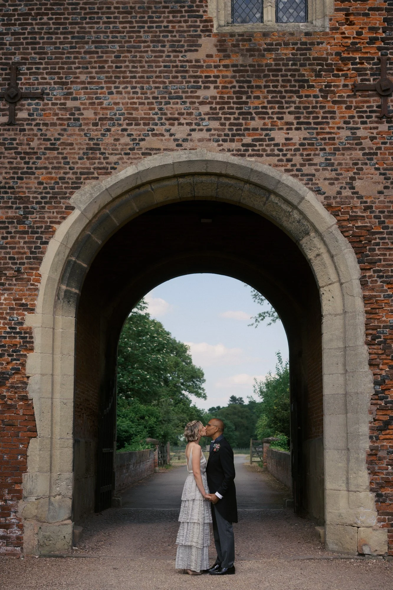  A couple kissing framed inside the brick arch of the Gatehouse at Hodsock Priory 