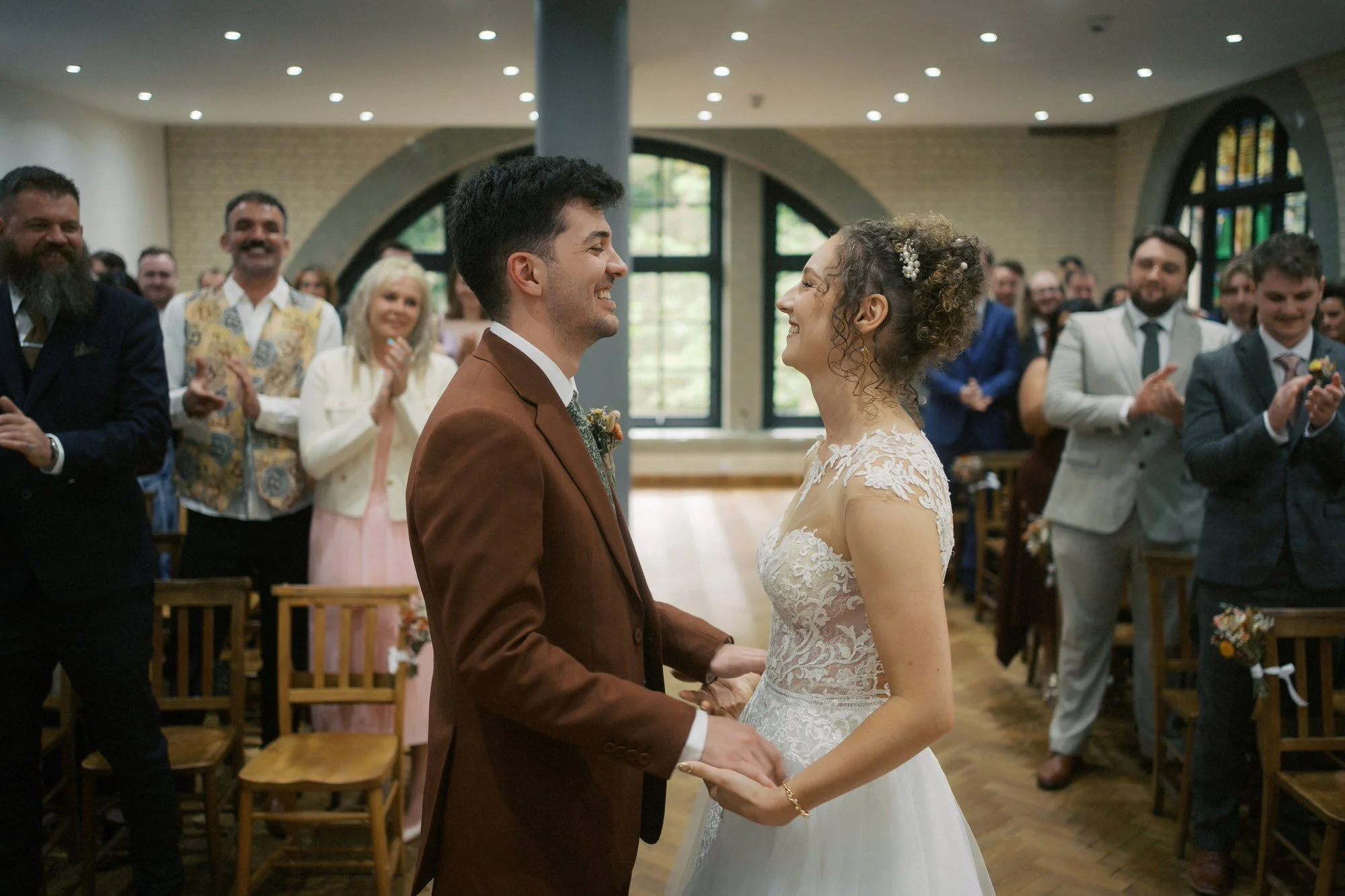  A groom and bride smiling at each other as guests applaud, The Pumping House, Ollerton 