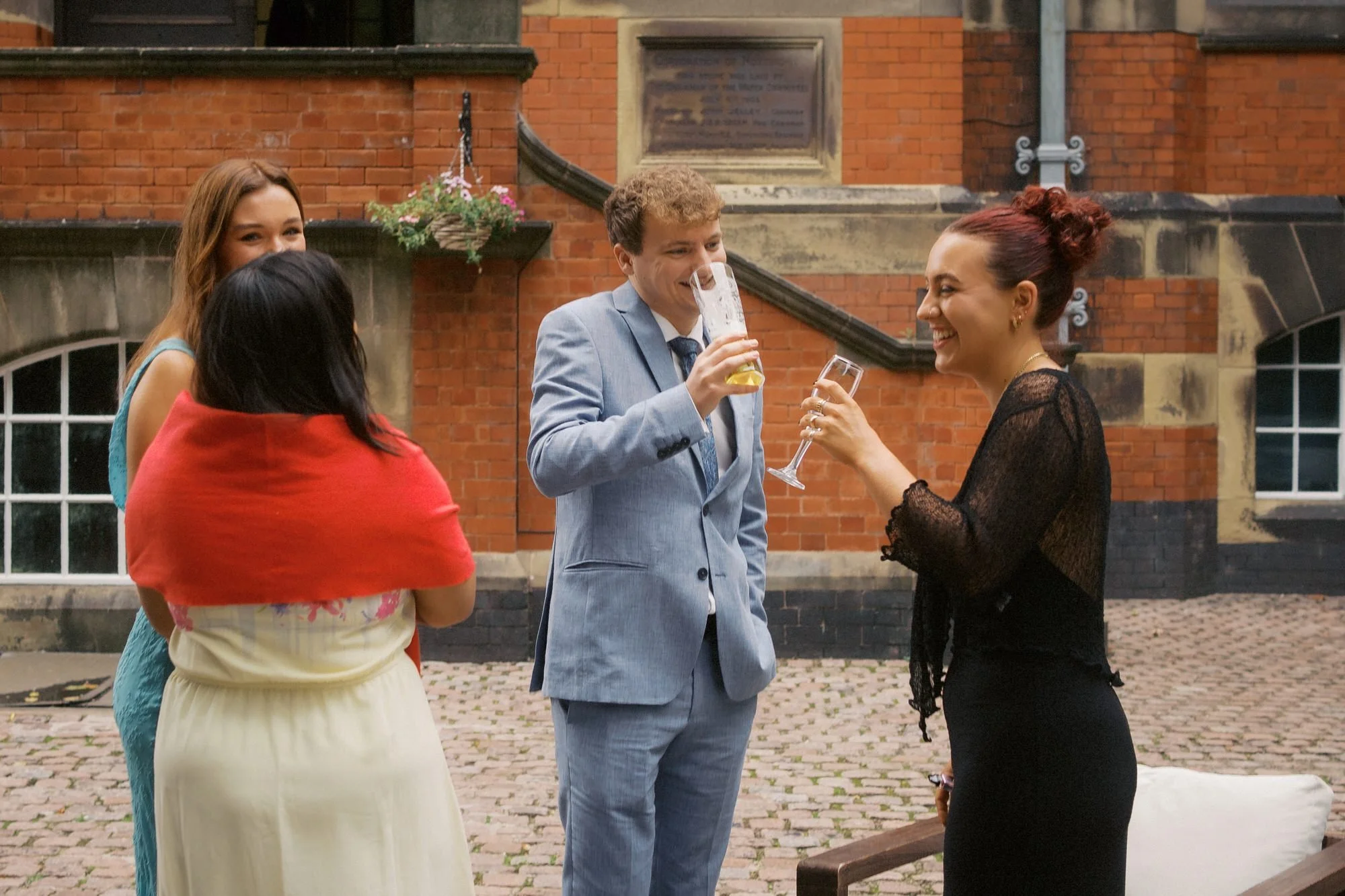  Wedding guests laughing over drinks on the cobbled courtyard at The Pumping House, Ollerton 