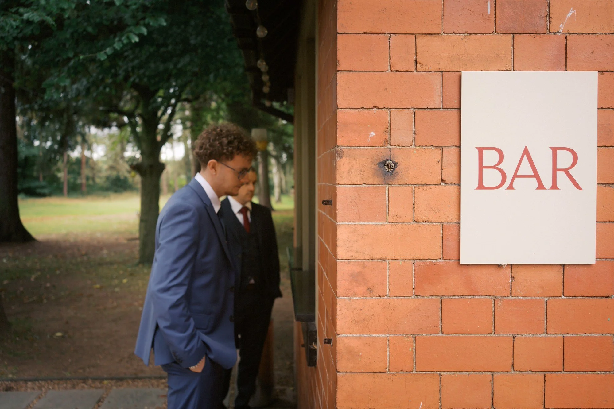  Two guests at the brick outdoor bar with a BAR sign, on the lawn at The Pumping House, Ollerton 