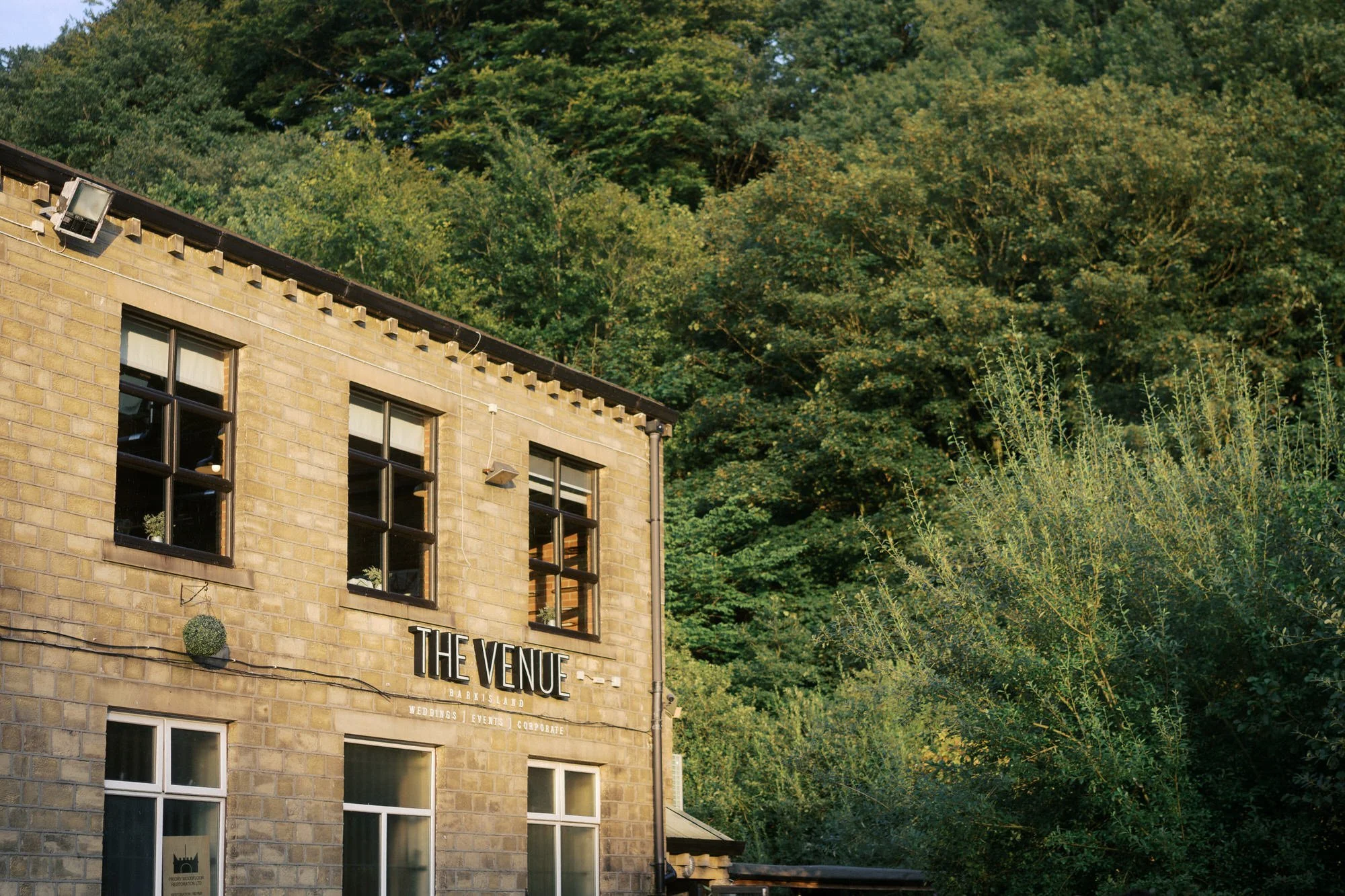The Venue sign on a sandstone building at Bowers Mill, Barkisland, in evening sun