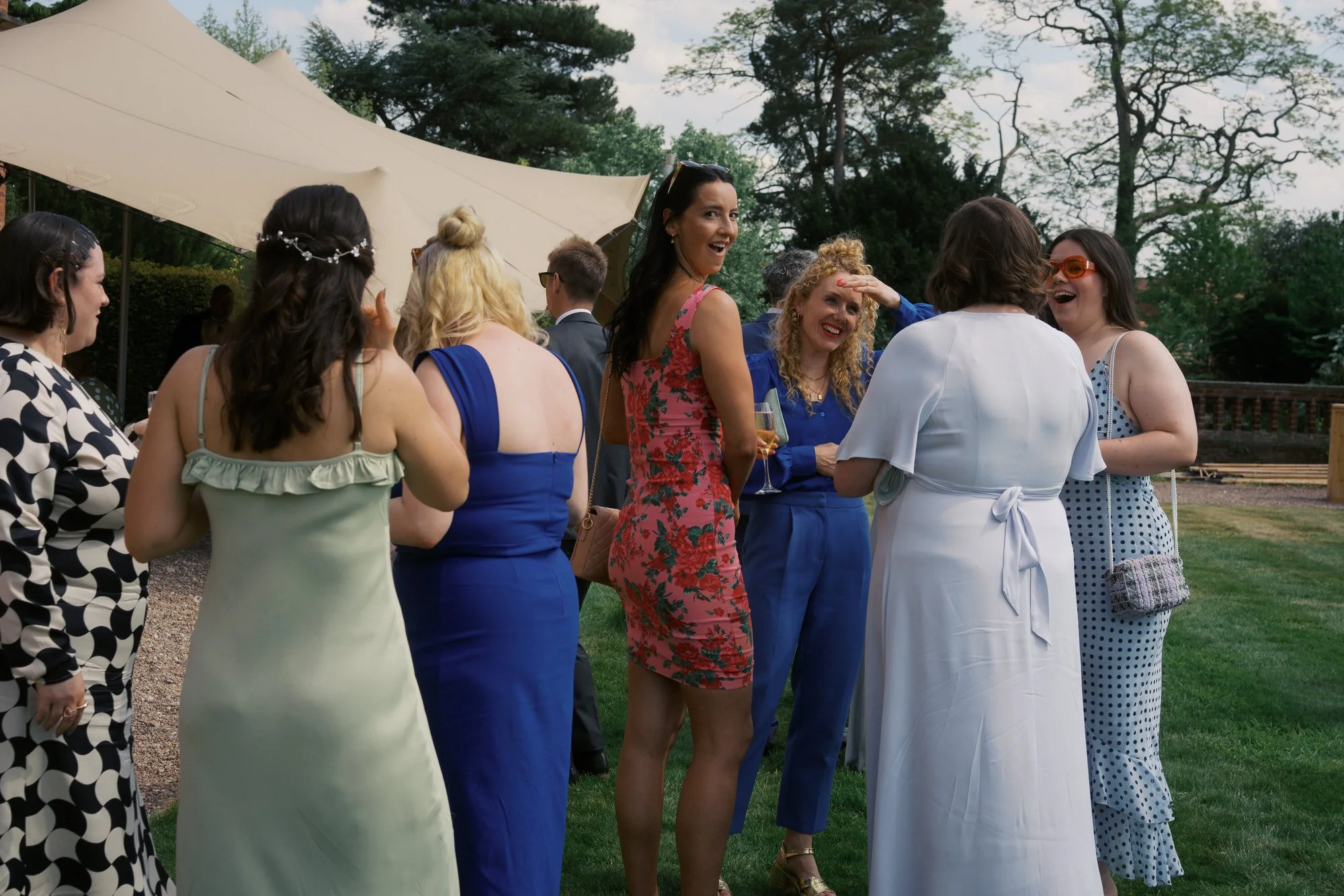 Wedding guests laughing together on the lawn of Hodsock Priory during the drinks reception
