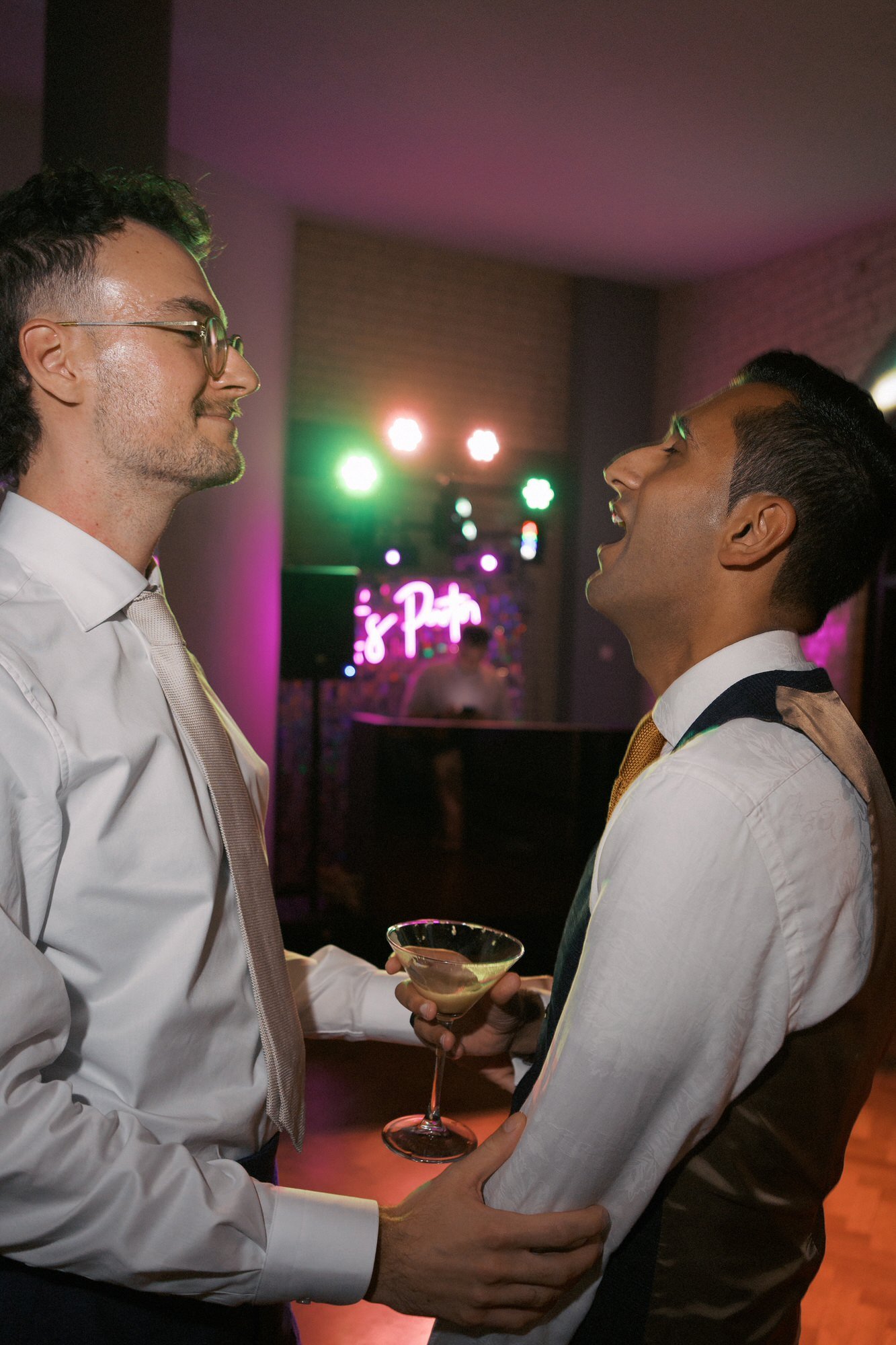 Two guests laughing together on the dance floor, the DJ booth behind, The Pumping House, Ollerton