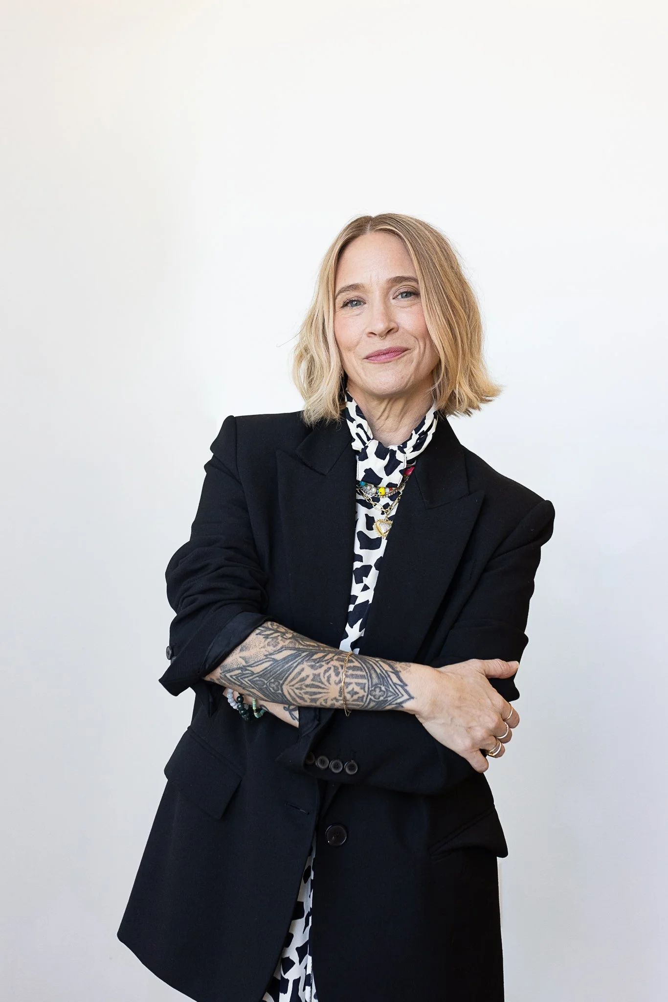 A stylist with a shoulder length blonde blunt bob wearing a long black blazer