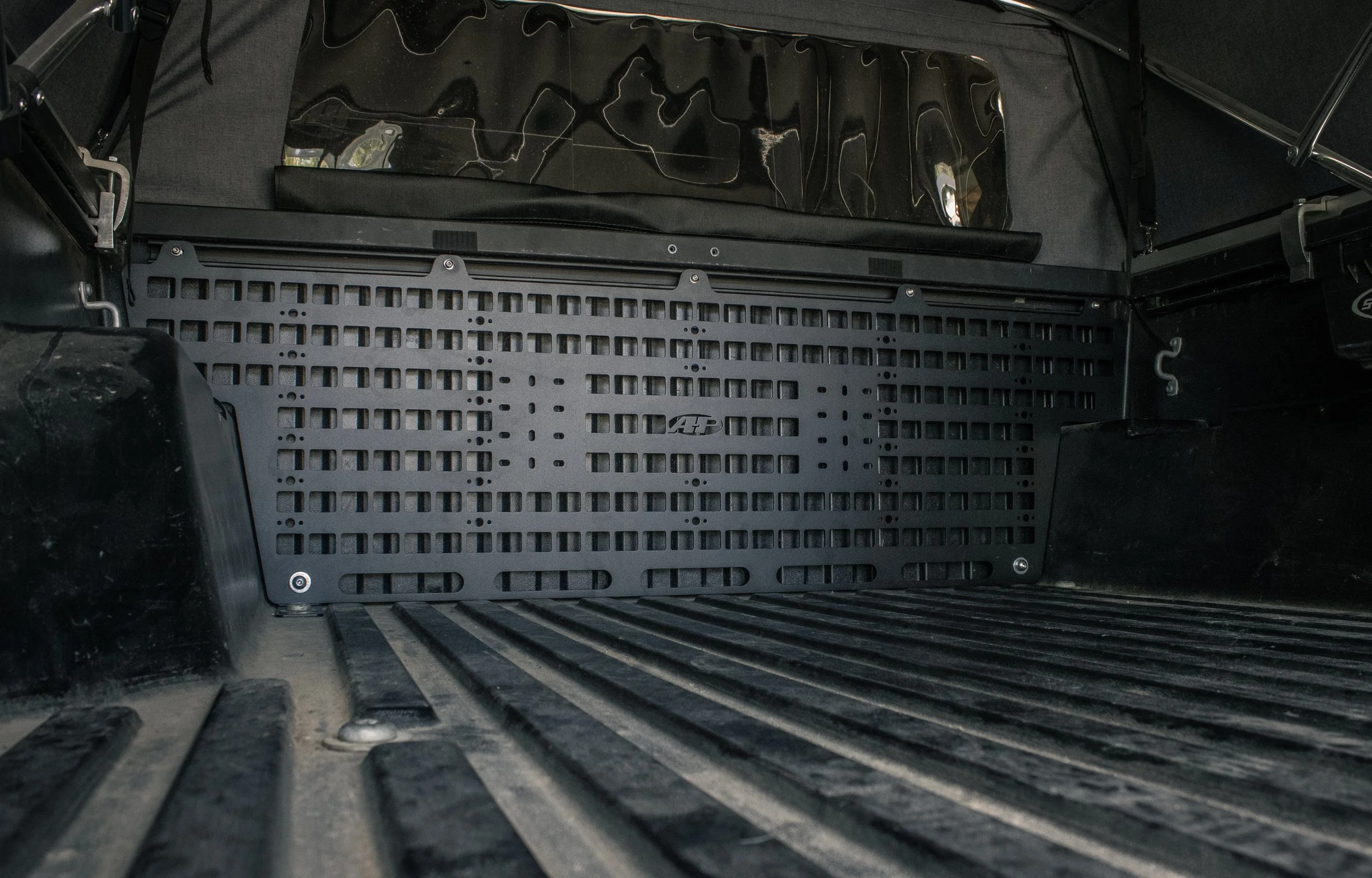 Interior of a Toyota Tacoma bed showing a bed molle panel mounted to the front.