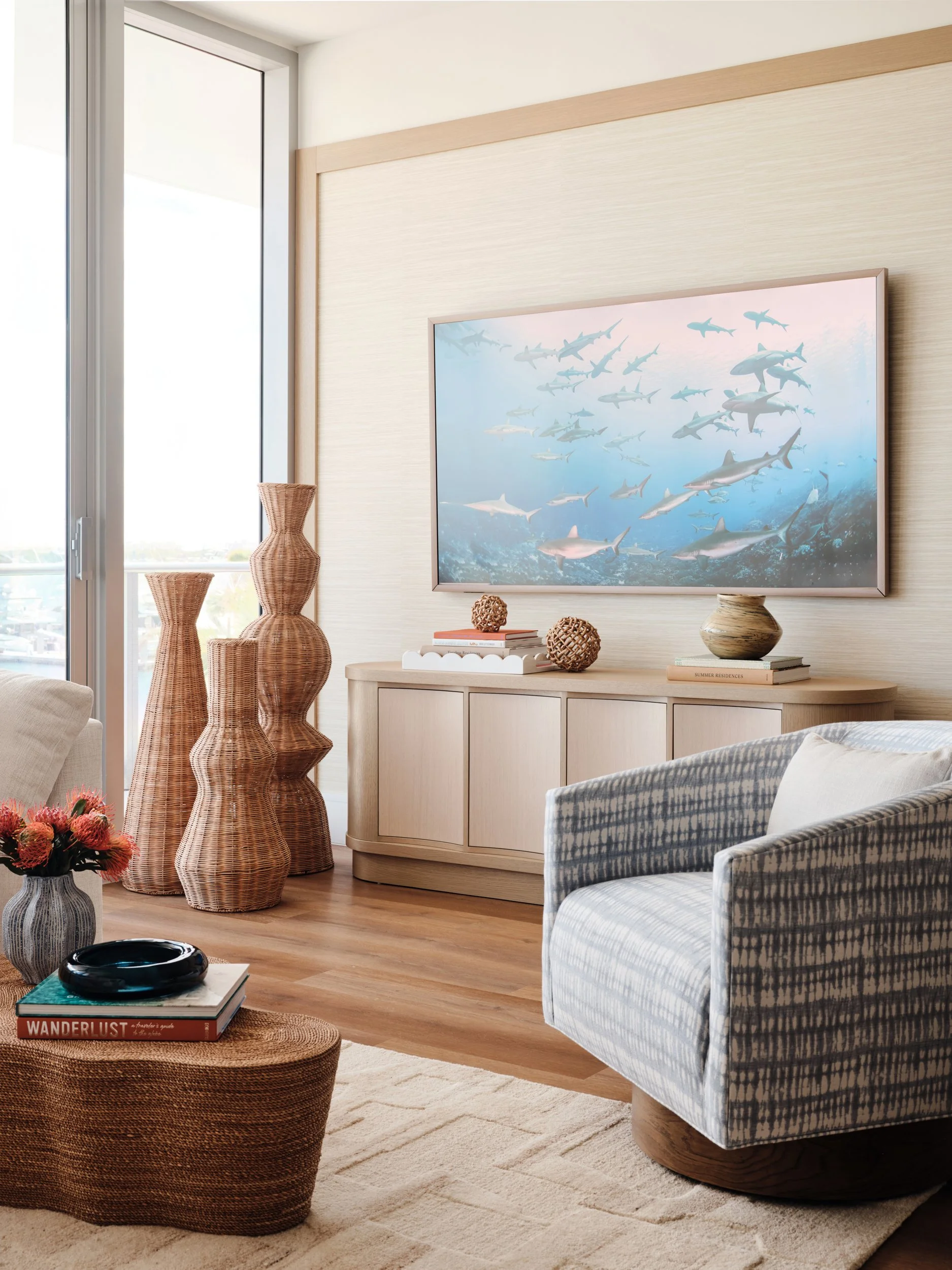 Curved oak media console with a shark scene, tall woven floor vases and an indigo-patterned swivel chair