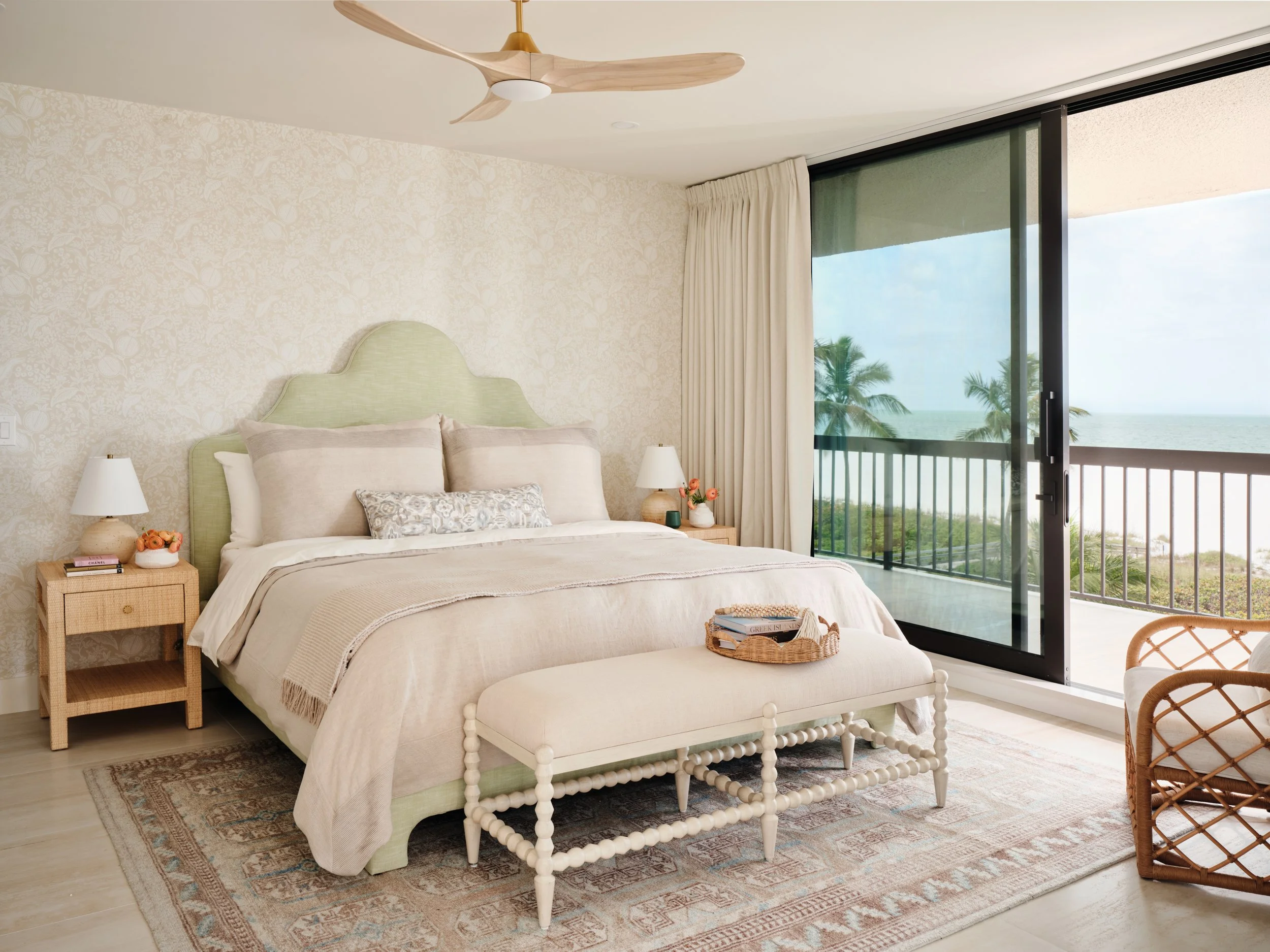 Primary bedroom in a Marco Island oceanfront condo with an arched sage headboard, woven nightstands and balcony views