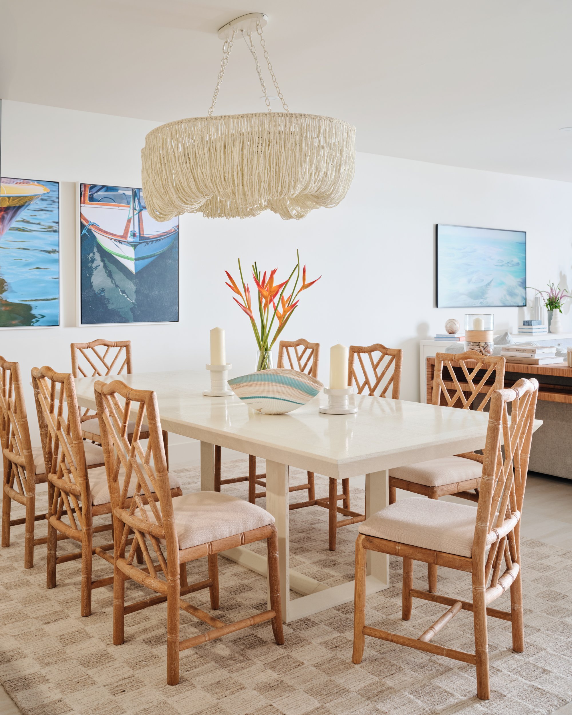 Dining room at The Duchess condo on Marco Island with a fringe chandelier, bamboo-style chairs and boat paintings
