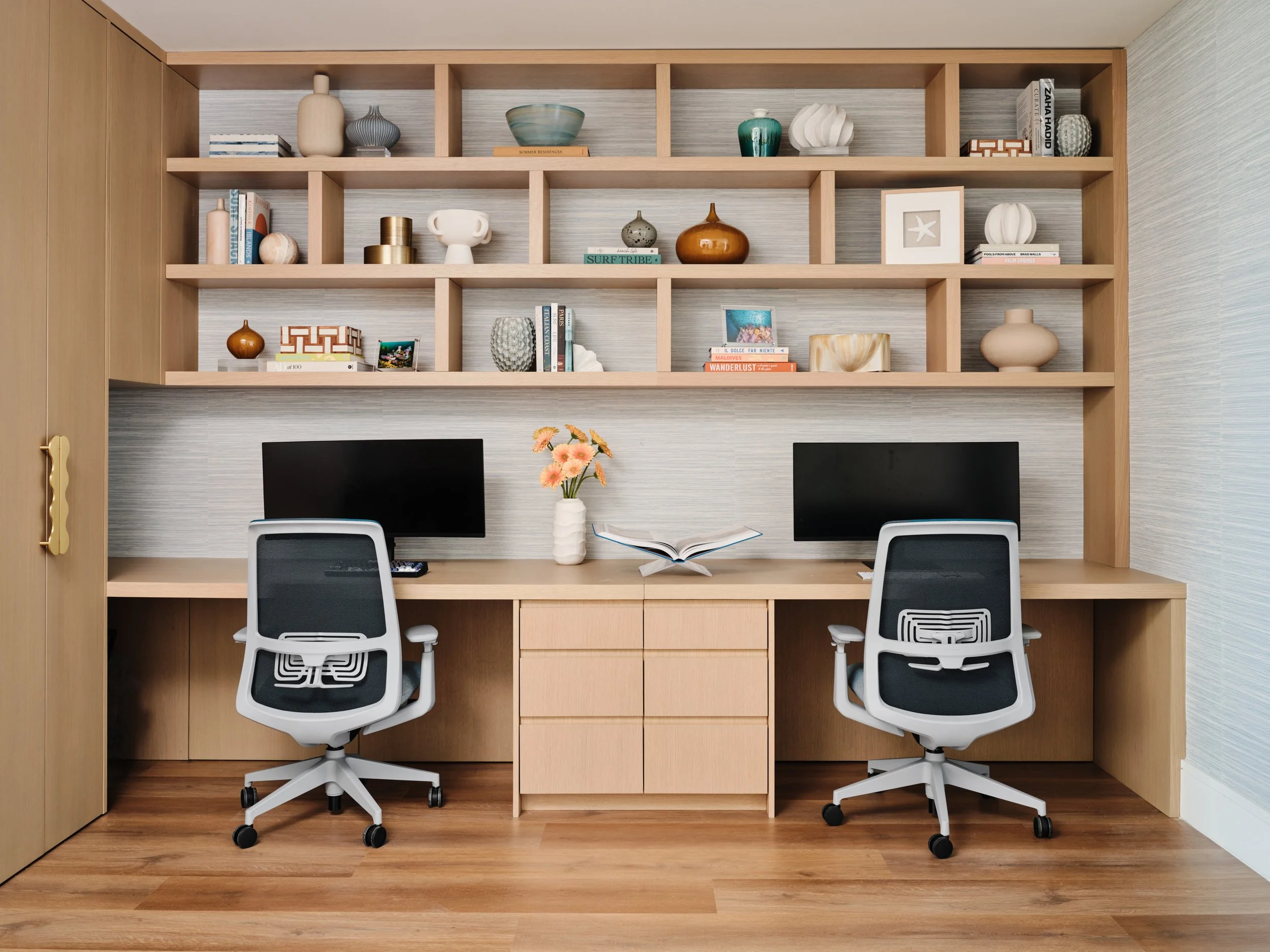 Custom white oak home office with a double desk, grasscloth-backed shelving and two desk chairs