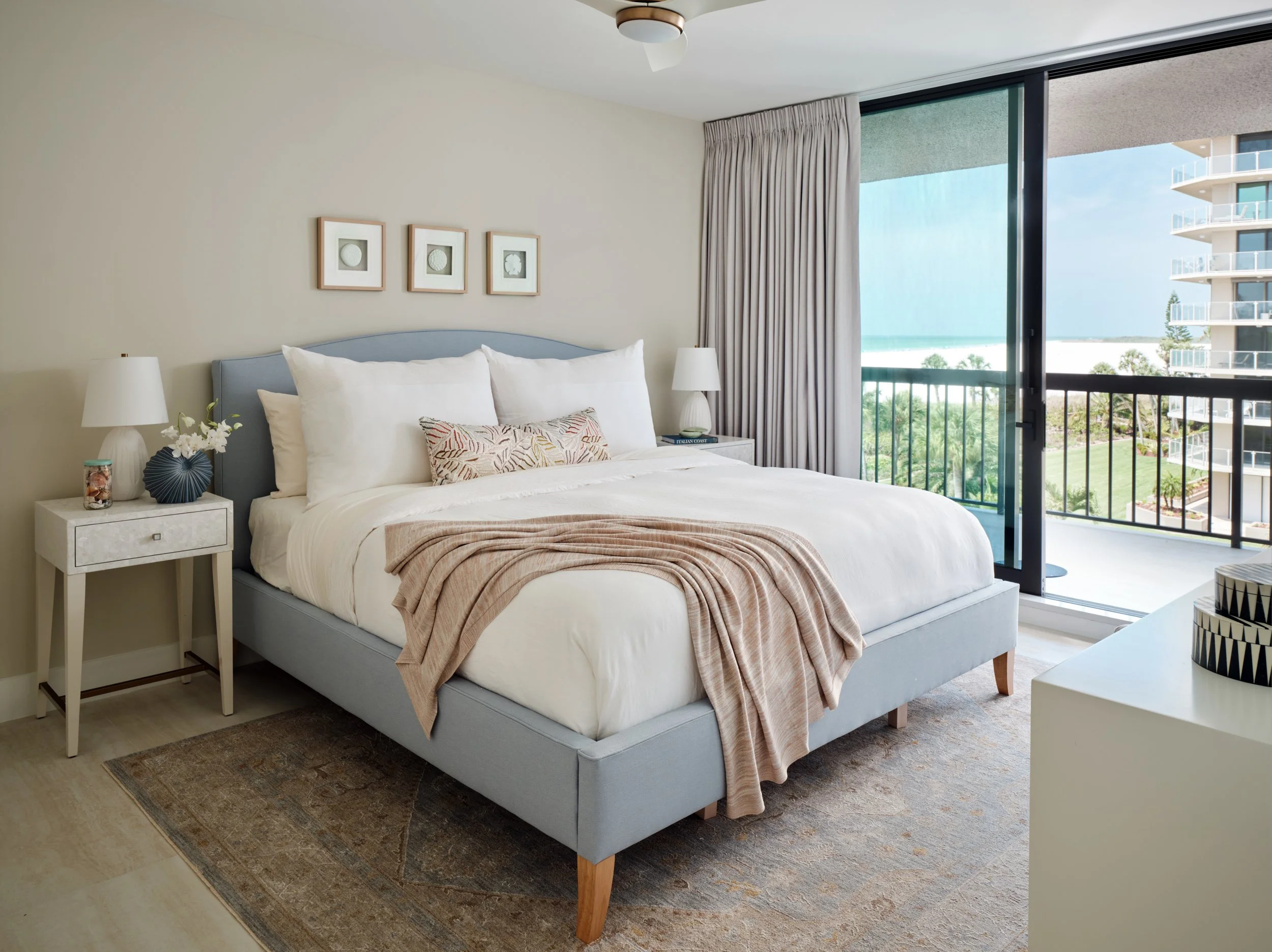 Guest bedroom in a Marco Island condo with a blue upholstered bed, white nightstand and framed sea urchin art