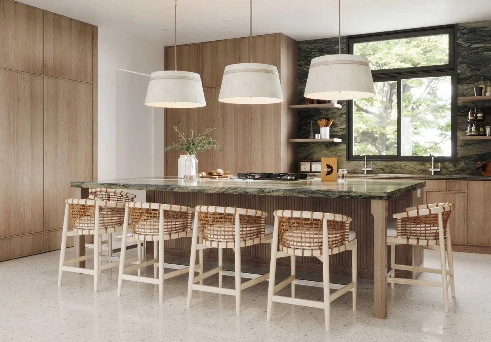Modern kitchen with a marble island, wooden cabinets, woven bar stools, and large windows showing greenery outside.