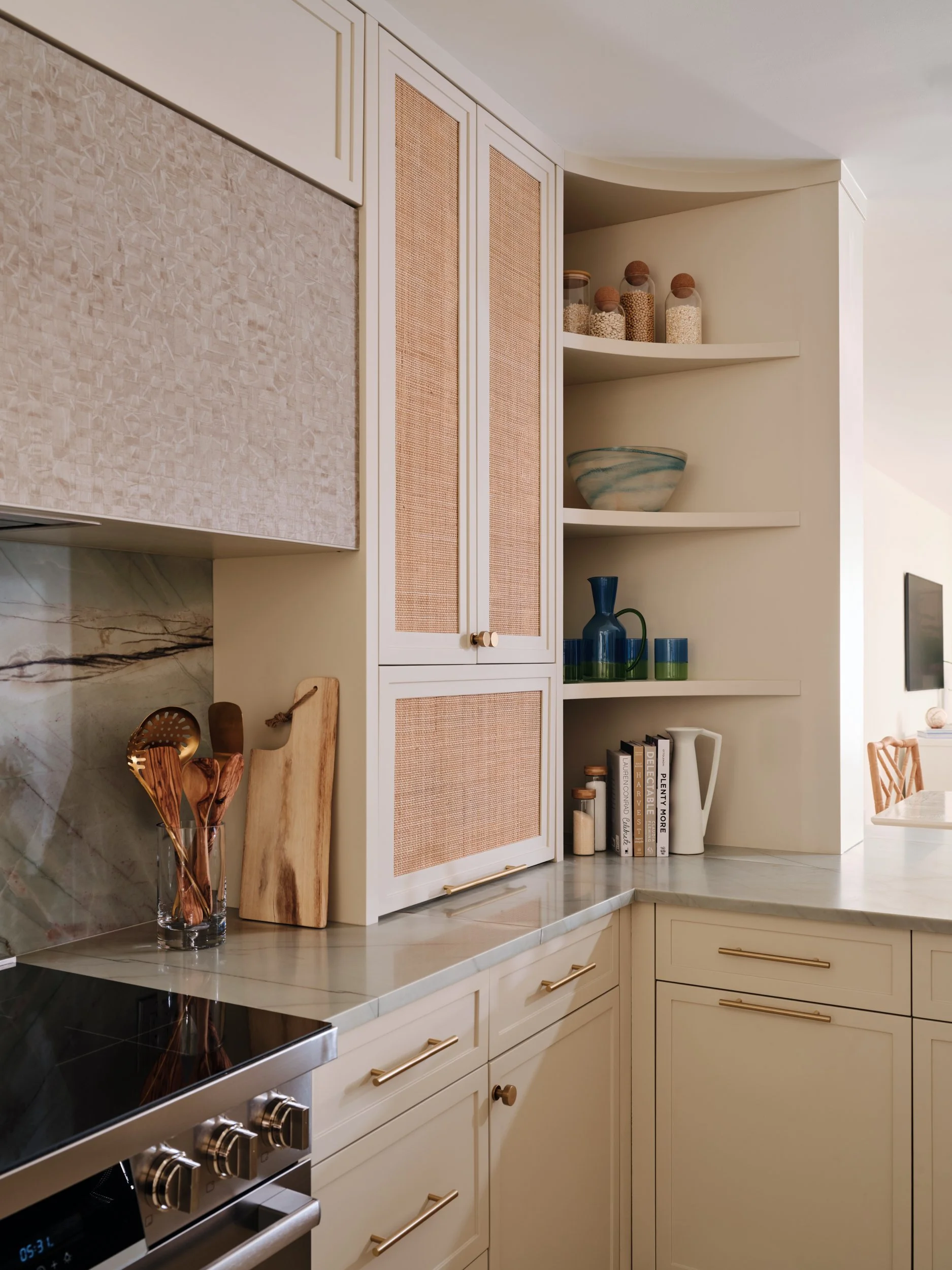 Curved open shelving and rattan inset cabinets in the kitchen of a Marco Island oceanfront condo