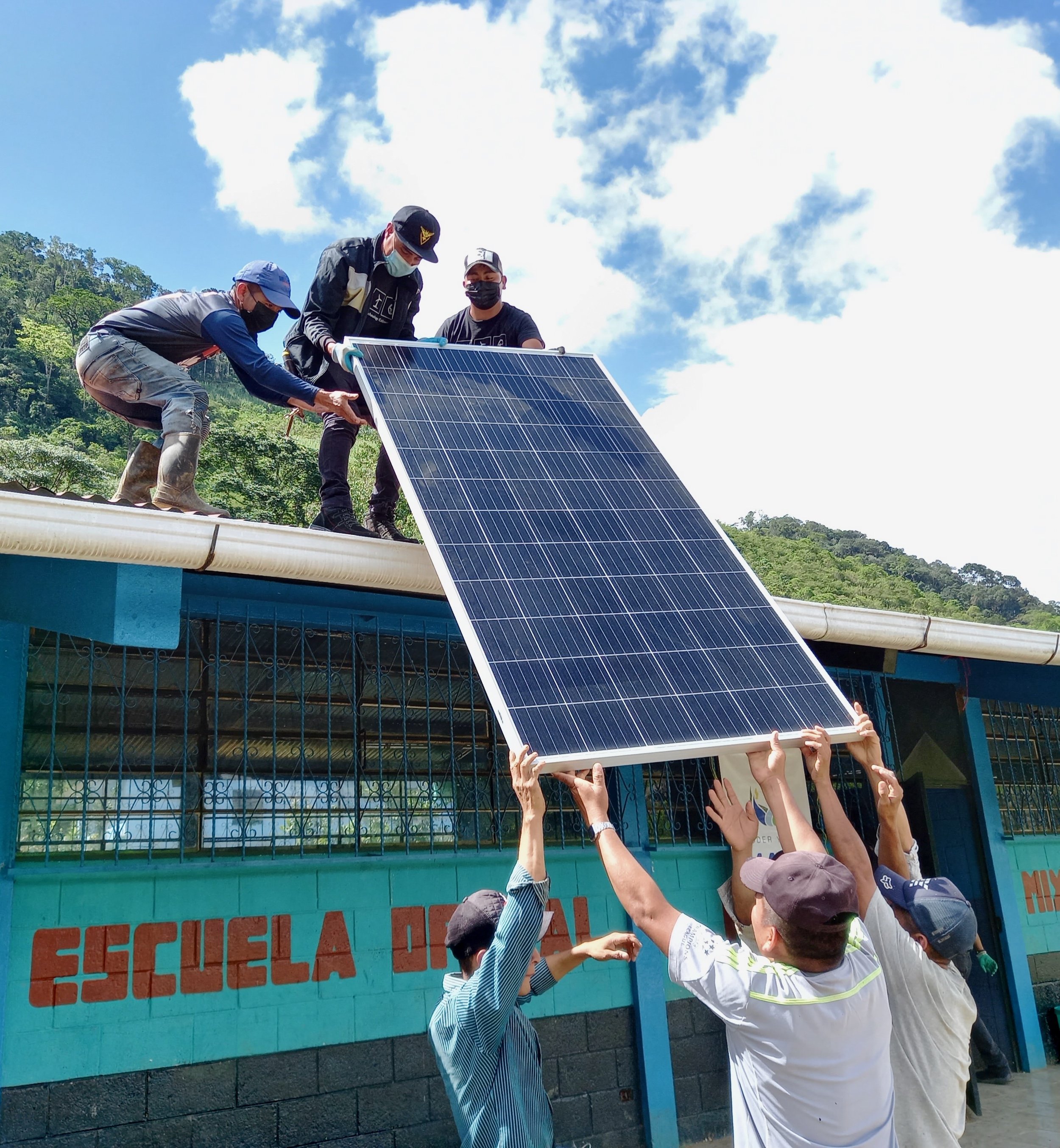 People installing solar panels on a building roof with a group of spectators watching.