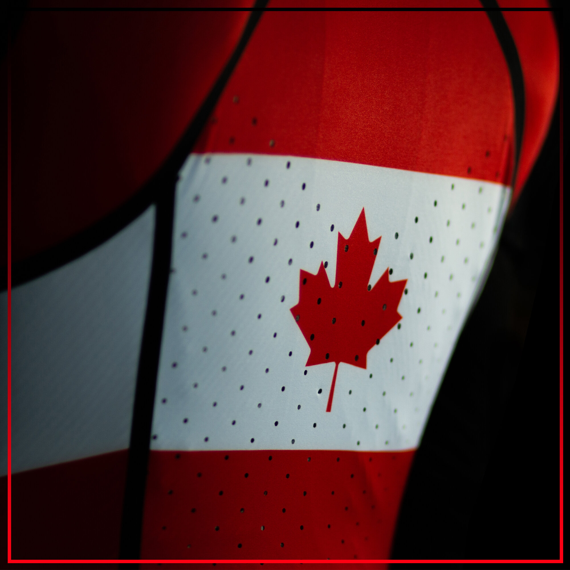 Close-up of a Canadian flag illuminated in red and white colors with black border overlay.