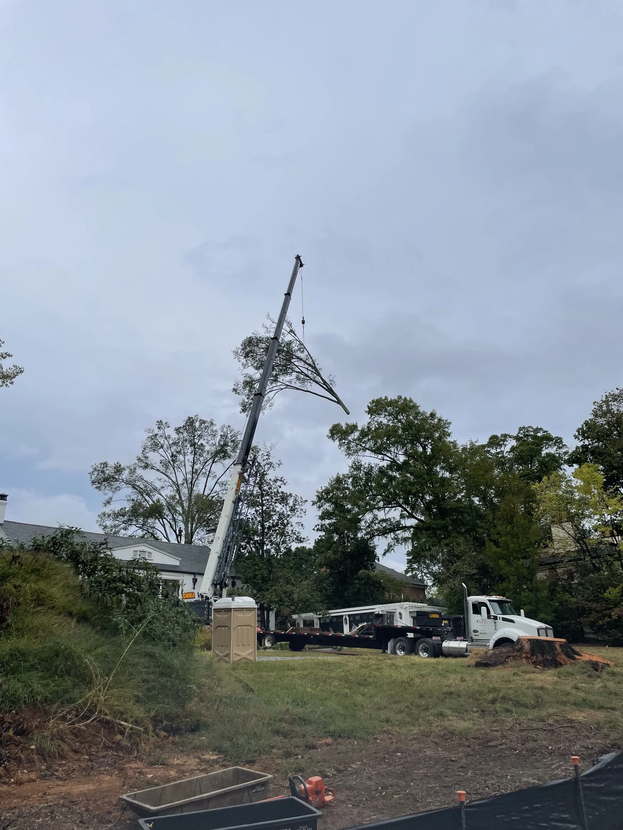 The crane raises the piece over the house, landscaping, and other items that could be damaged and moves it to a clear area to be processed.