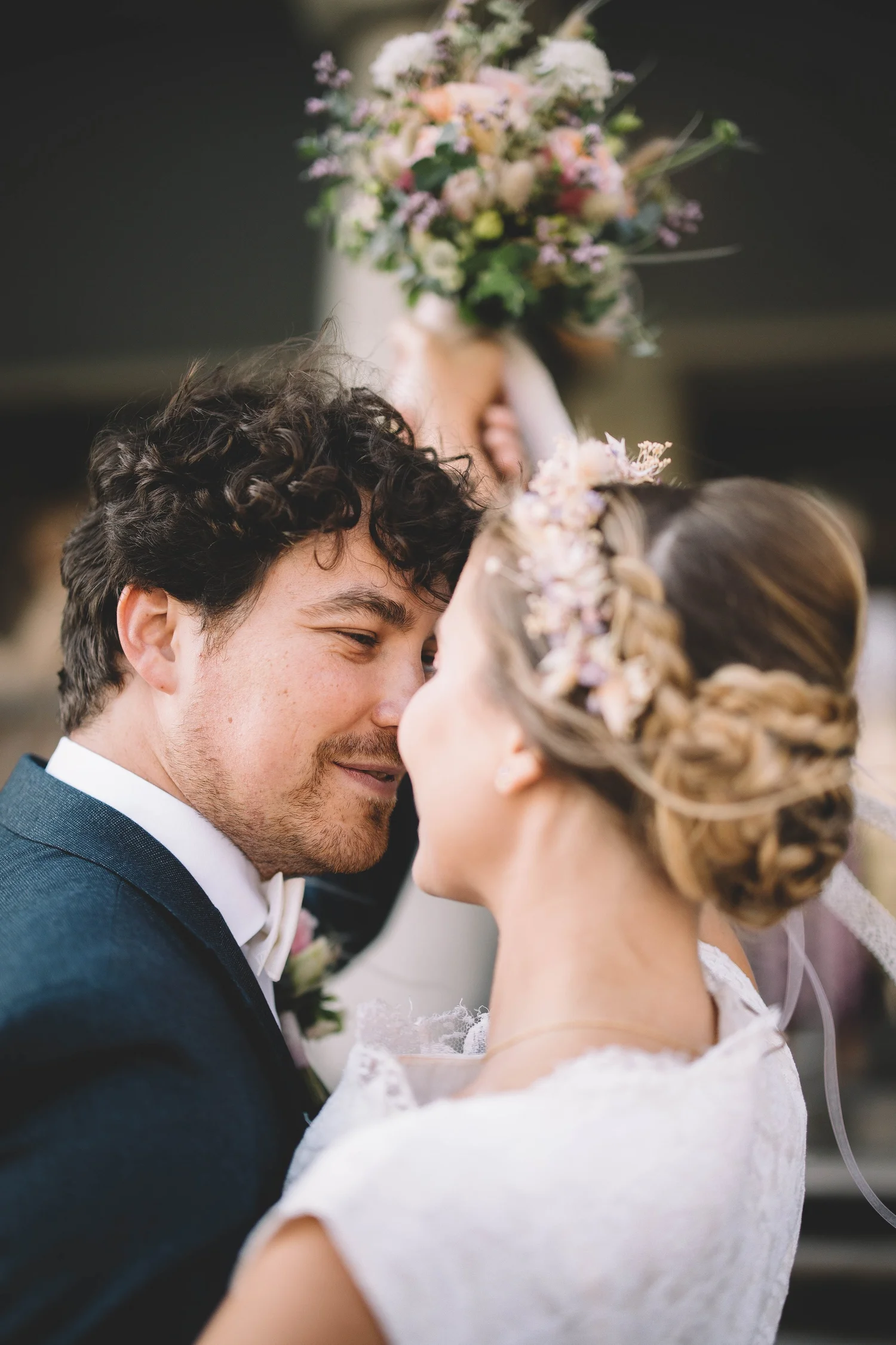 Ein Brautpaar während ihrer Hochzeit, sich näherten mit der Braut, die eine Blumenkrone trägt, und dem Bräutigam in einem dunklen Anzug, wobei sie sich nahekommen.