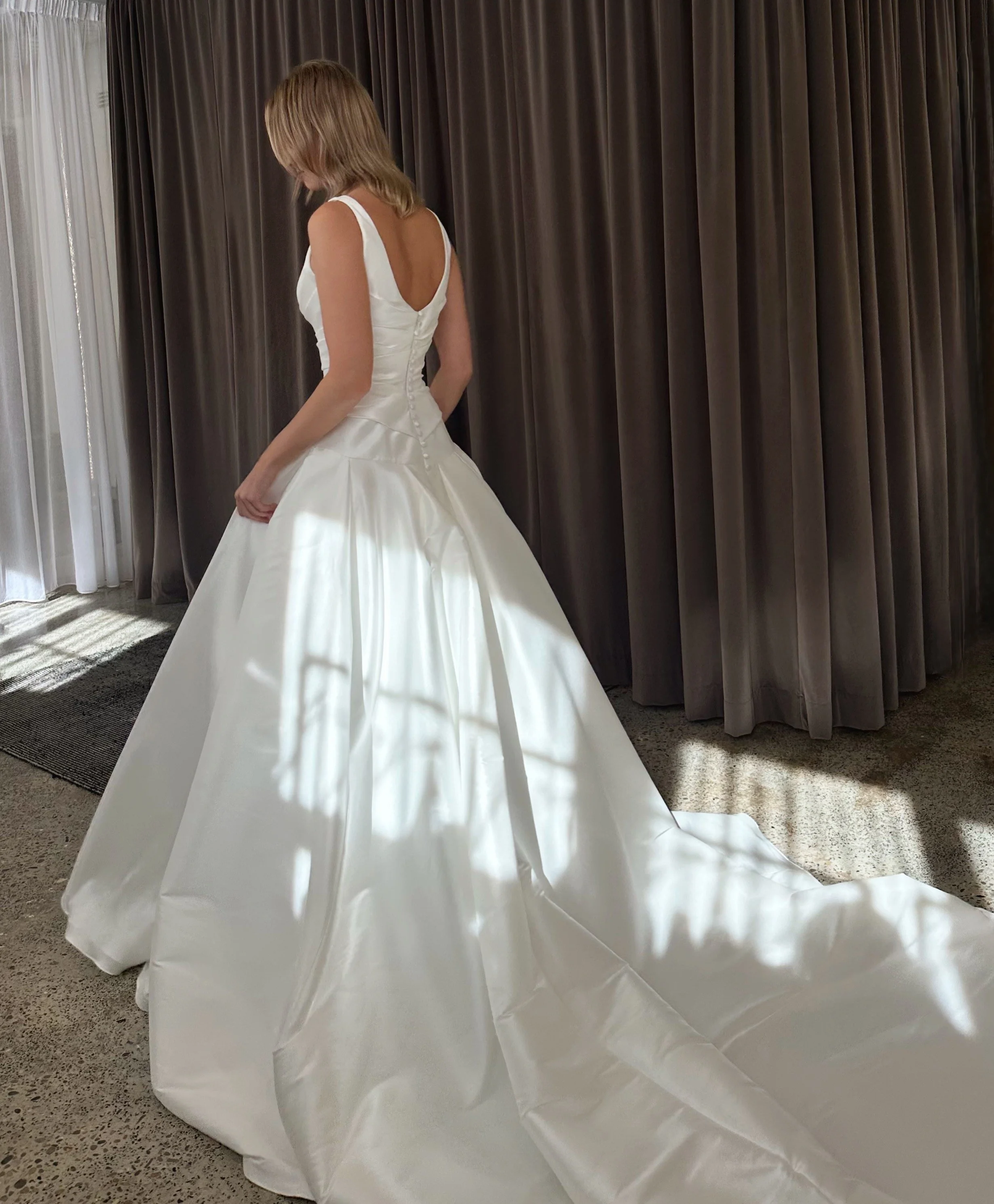 Designed for the modern bride with a love for classic silhouettes, this gown features a beautifully structured bodice that flows into a dramatic full skirt and sweeping train. Crafted in luxurious ivory Mikado, it creates a striking silhouette with c