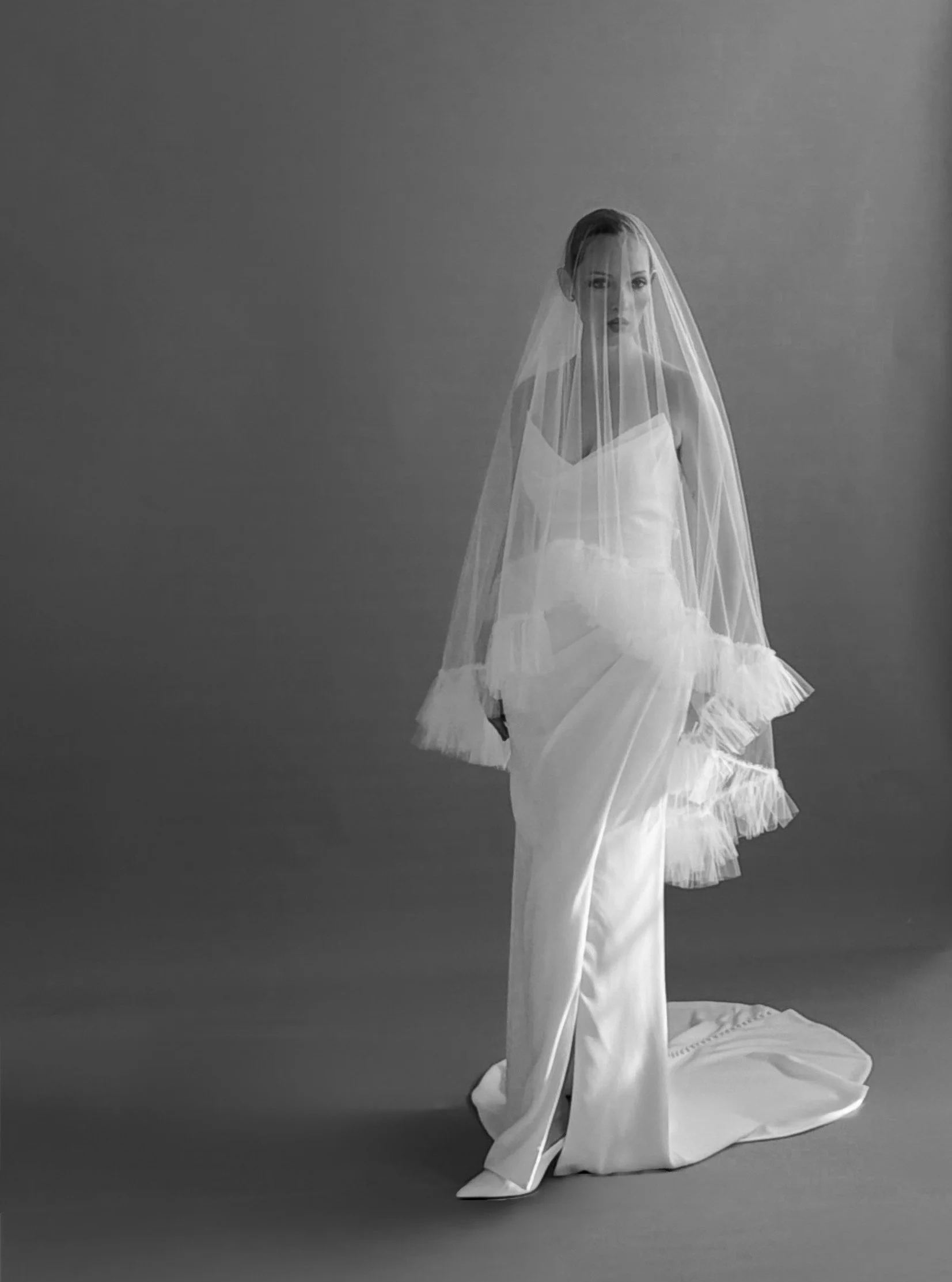 Some details don't just complete the look they transform it.
Crafted from the softest illusion tulle, this statement veil is finished with cascading pleated ruffles that frame every movement with effortless romance. Paired with Alexandra gown, it cre