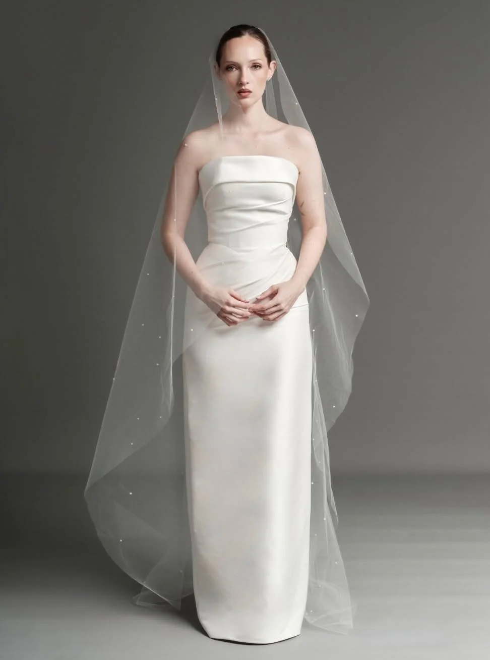 Beautifully considered, our sculpted Ava gown, paired with one sheer O shape chapel veil scattered with delicate pearls. Effortlessly romantic, a bridal look that feels timeless from every angle.
For the bride who believes less can say so much more.