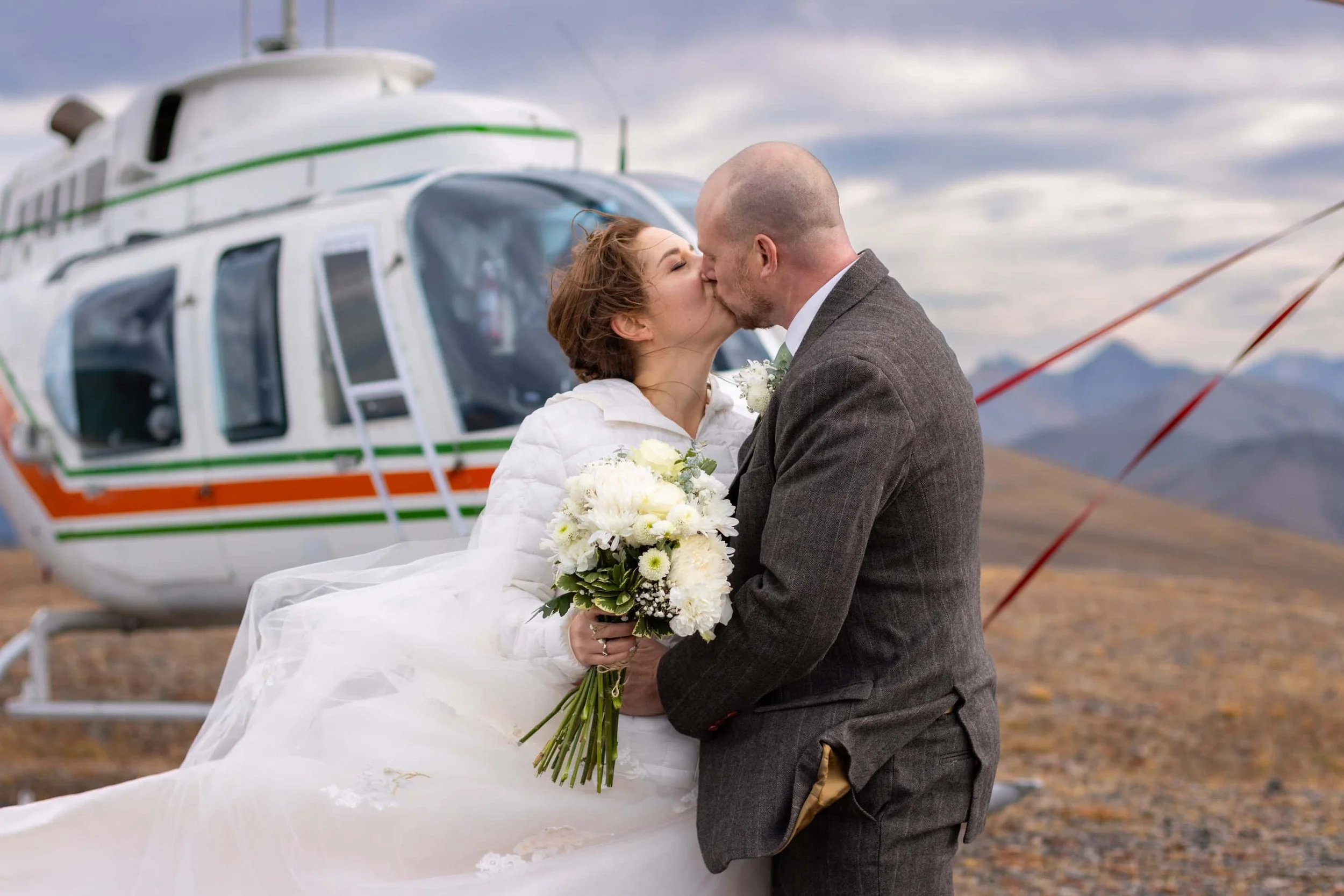 Couple kissing in front of the helicopter during their elopement