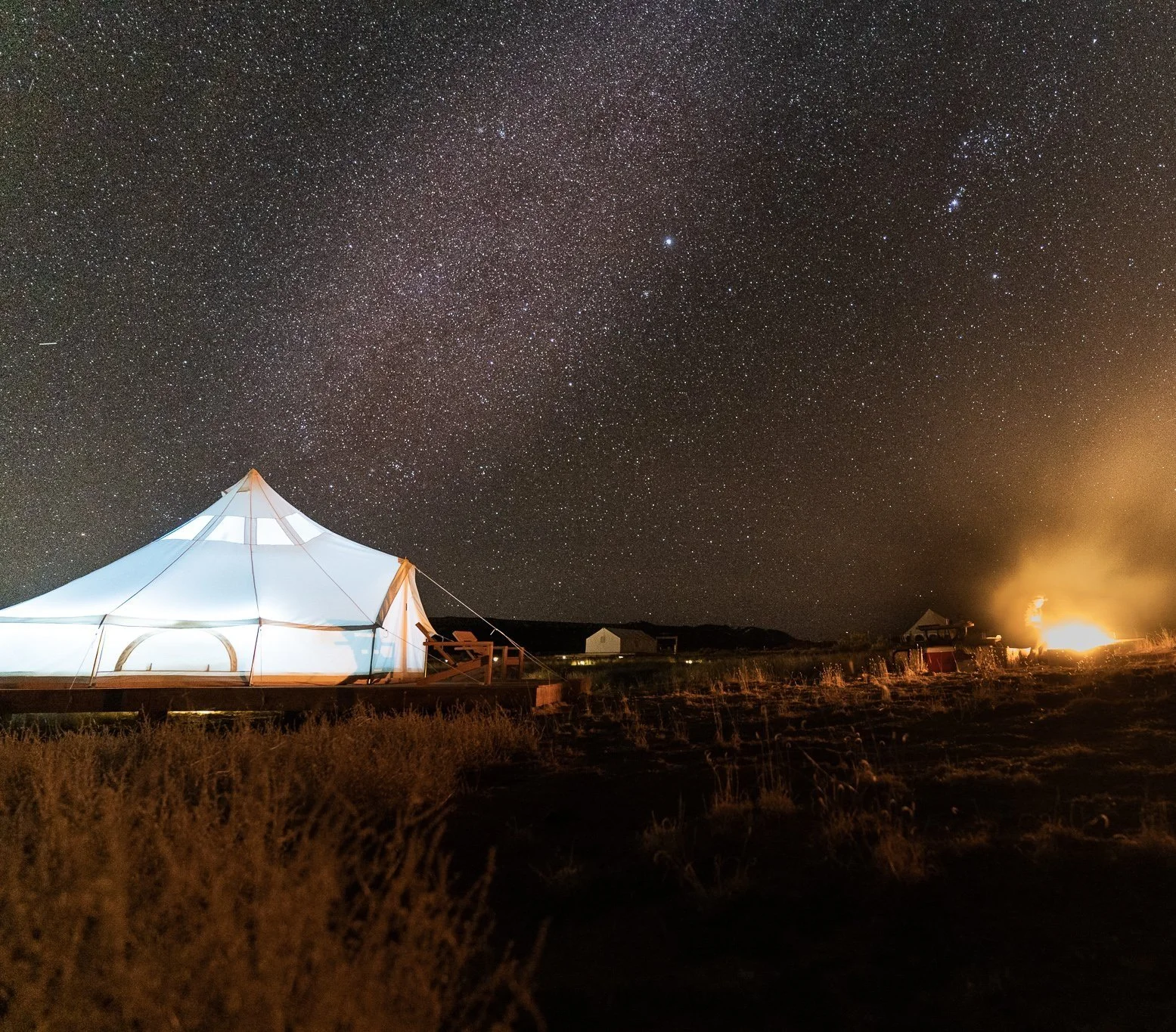 A glamping tent with a campfire under the milky way