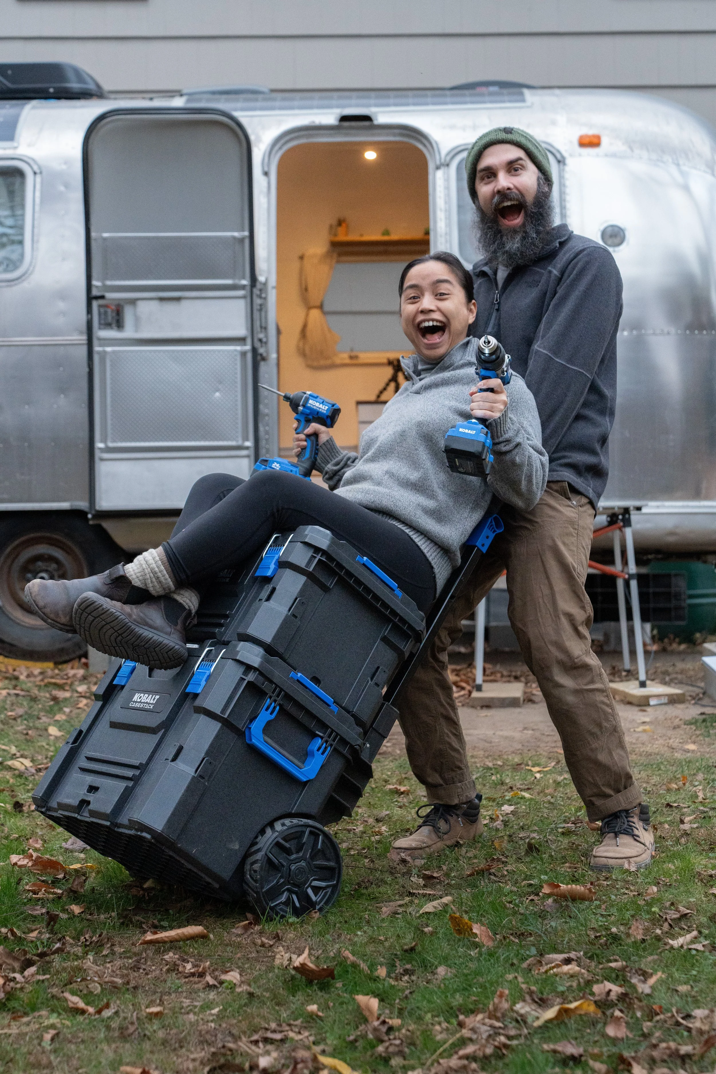 A couple posing in front of the camera showing Kobalt Case Stack and Kobalt tools in front of an airstream