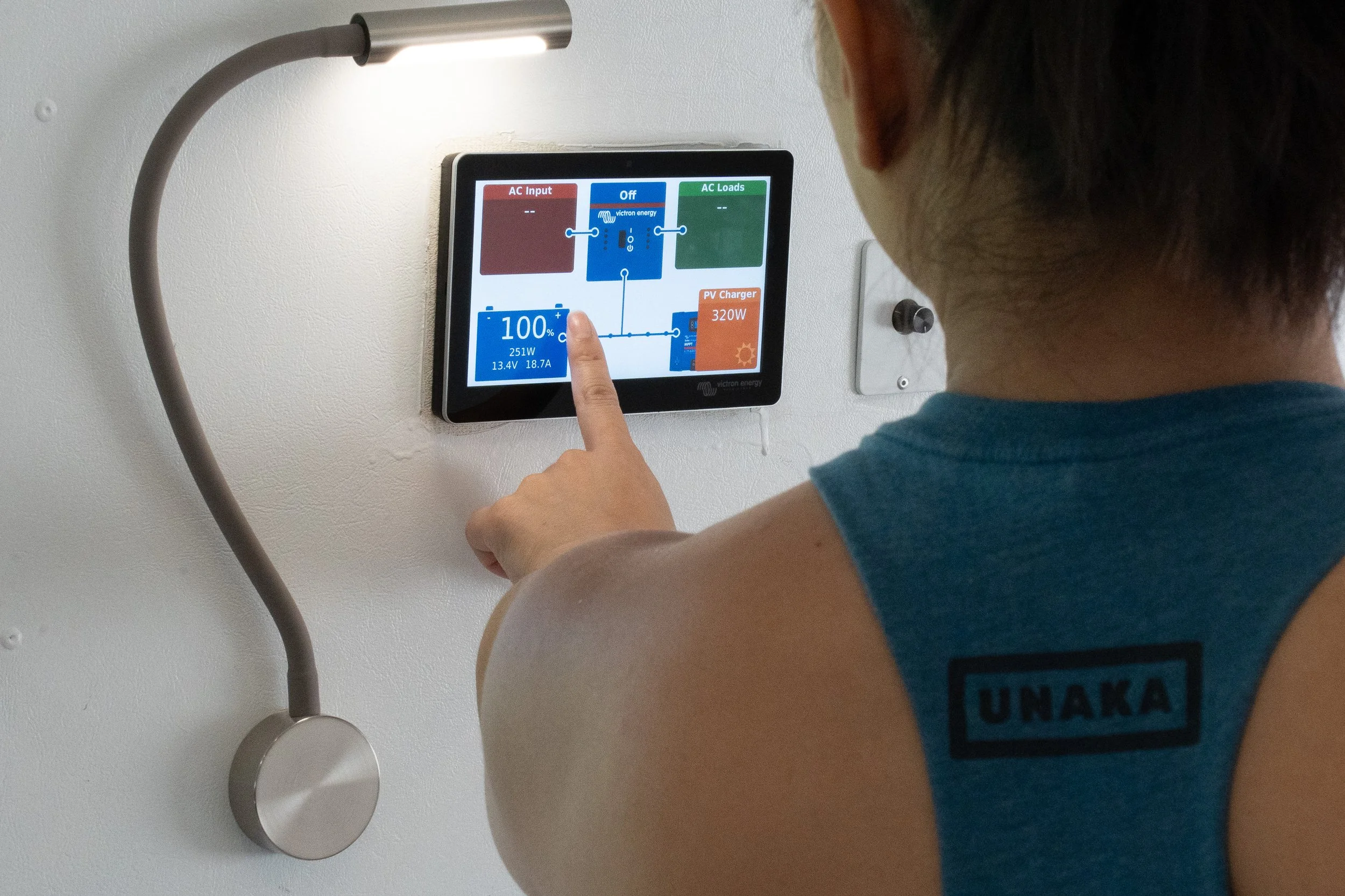 A woman using a Victron Cerbo GX to monitor an off-grid electrical system