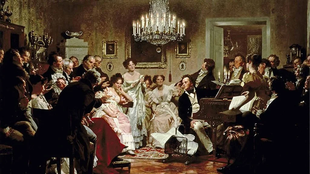 A group of people in 19th-century clothing gathered in a richly decorated room, listening to a woman singing and playing a piano.