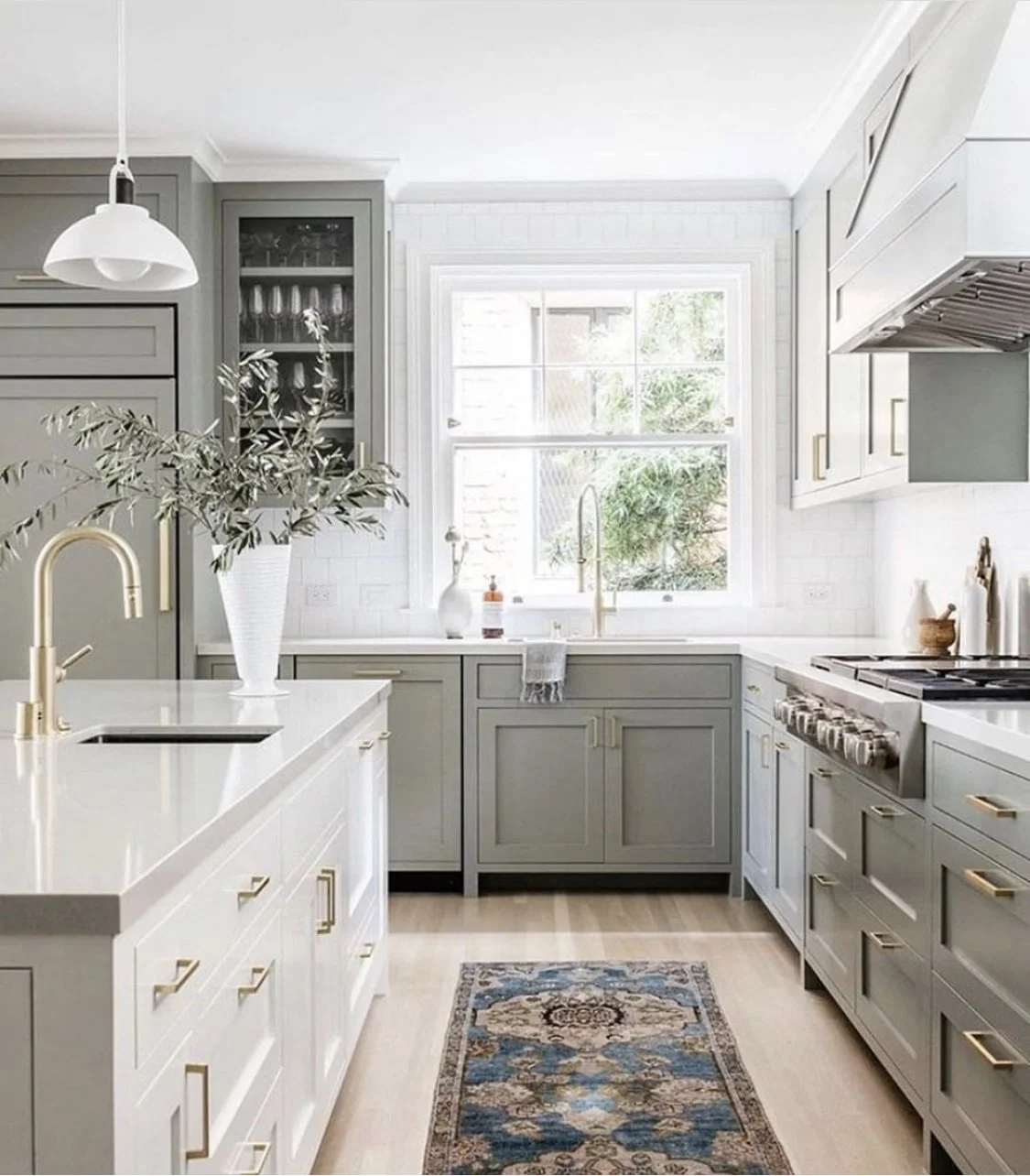 Elegant kitchen design with sage green cabinets, white quartz countertops, brass hardware, and a Persian runner.