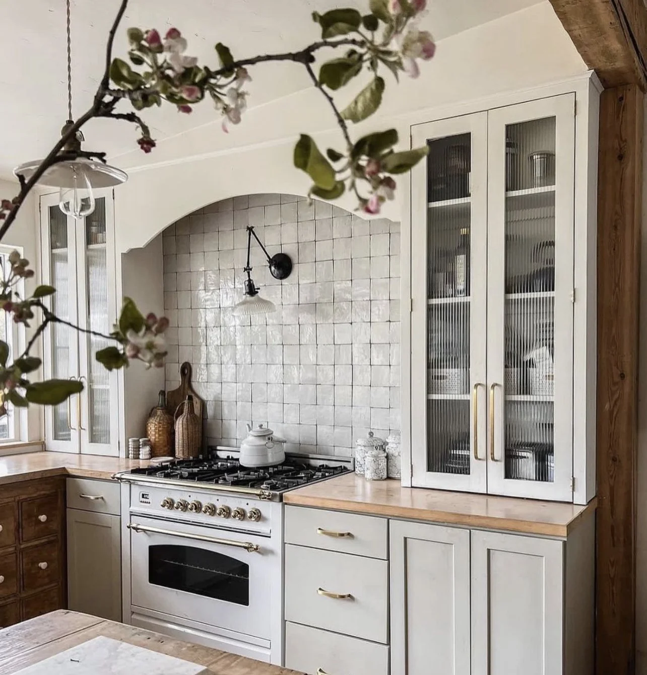 Charming cottage-style kitchen with a vintage-style white range, zellige tile backsplash, and glass-front cabinets.