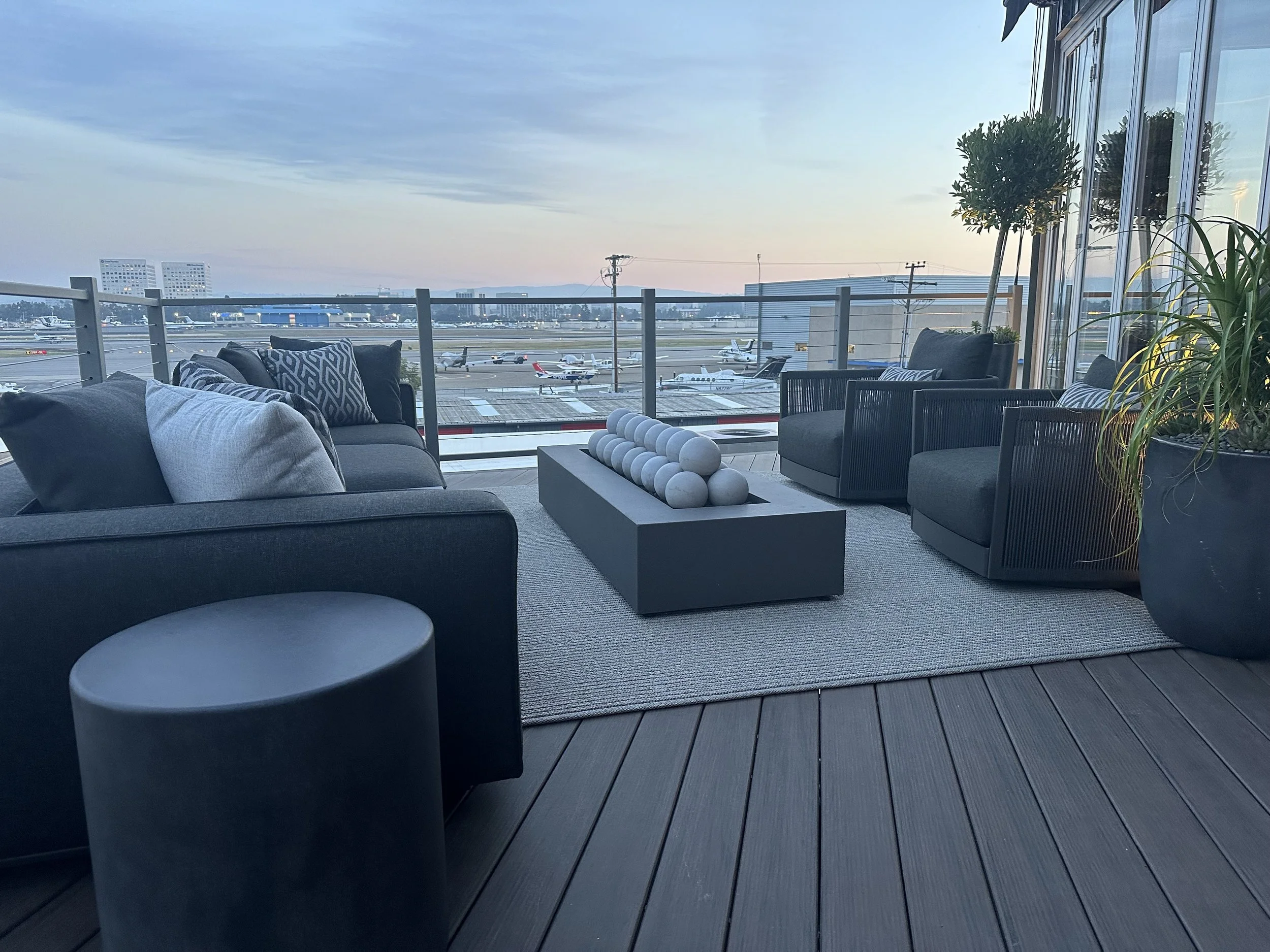 Stylish rooftop terrace with modern furniture, sculptural firepit, and private runway at sunset