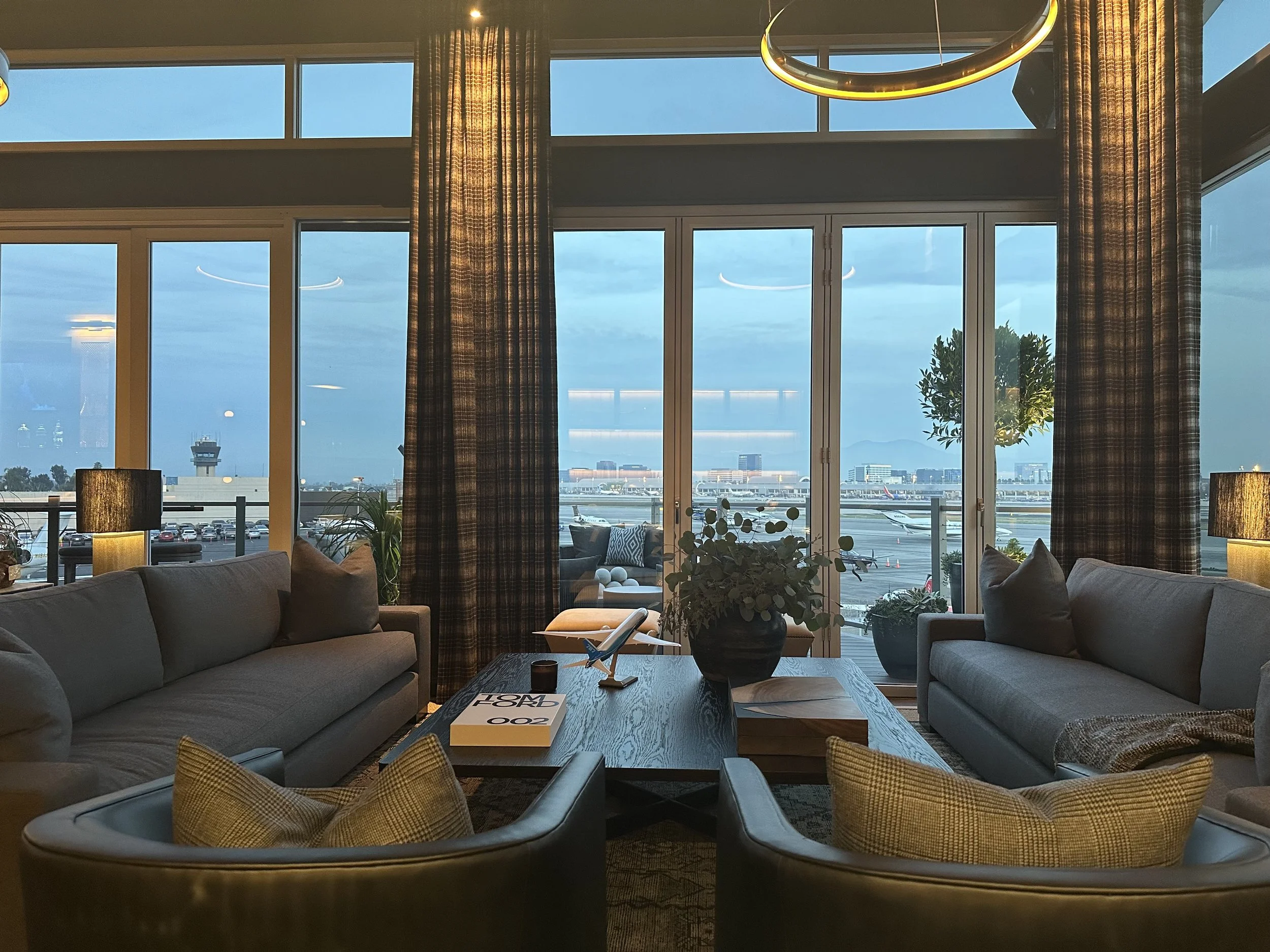CEO office with expansive airport runway views, cozy lounge setup, and elegant evening lighting