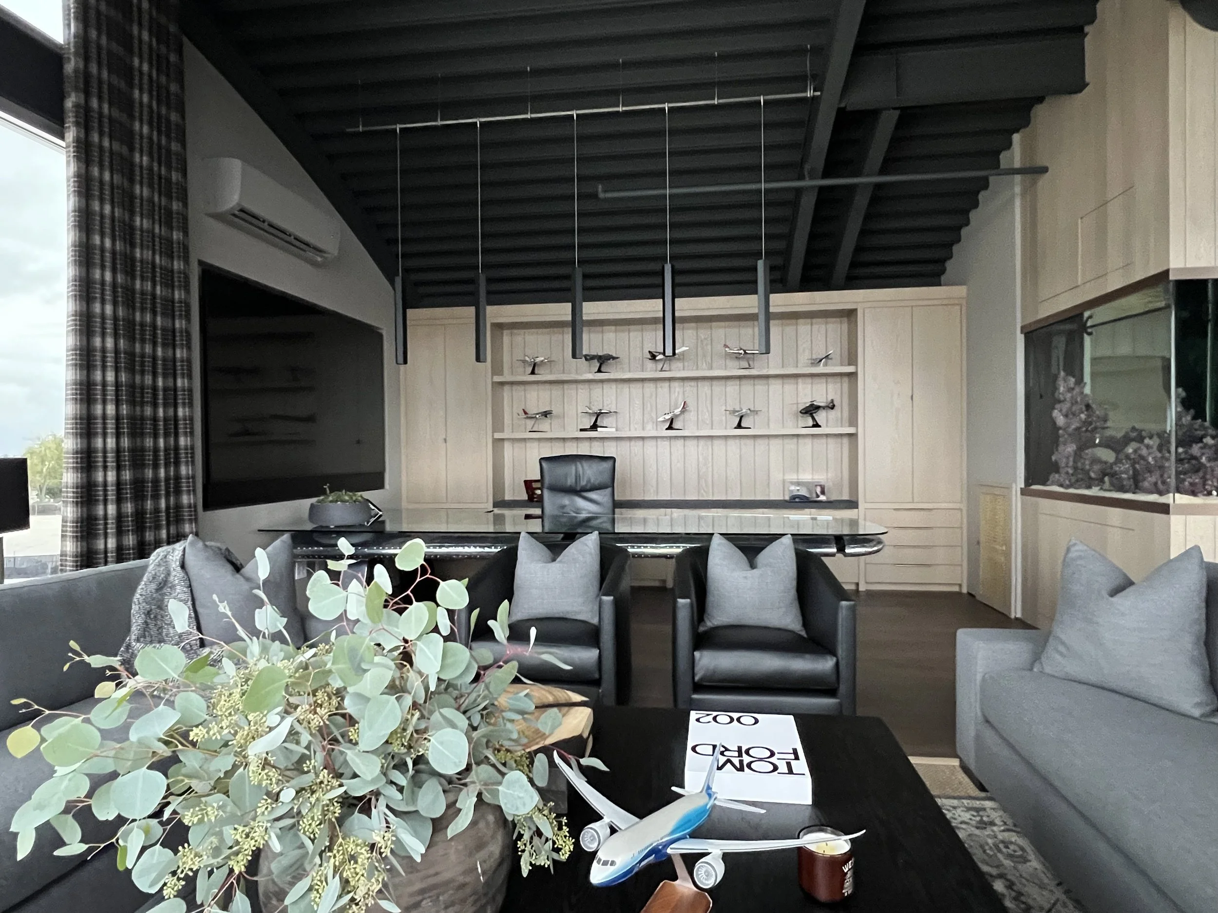 CEO office with model airplanes on display, glass desk, designer lounge setup, and coffee table decor