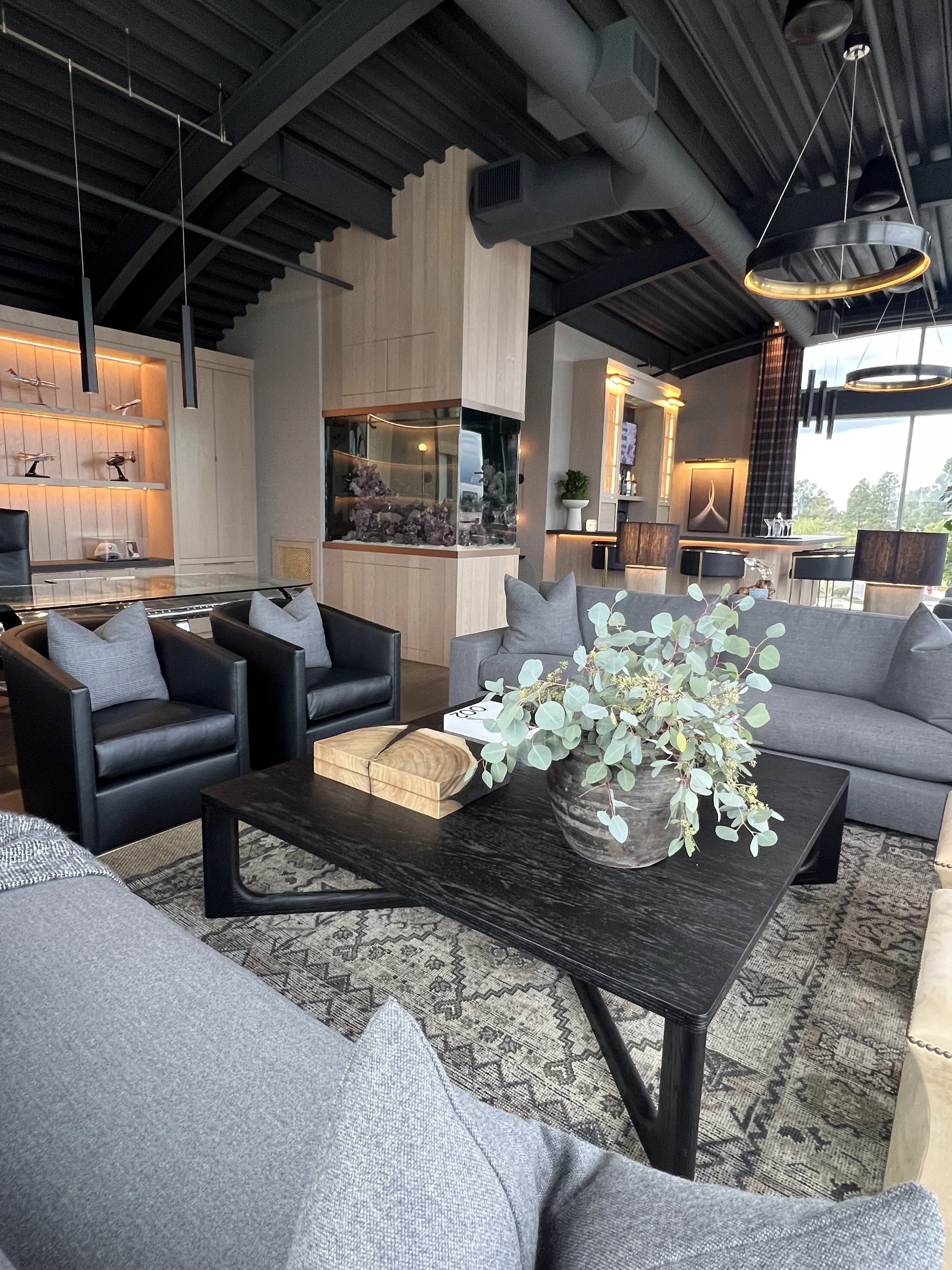 Modern CEO lounge with grey sofas, aquarium feature, glass coffee table, and ambient lighting in executive suite