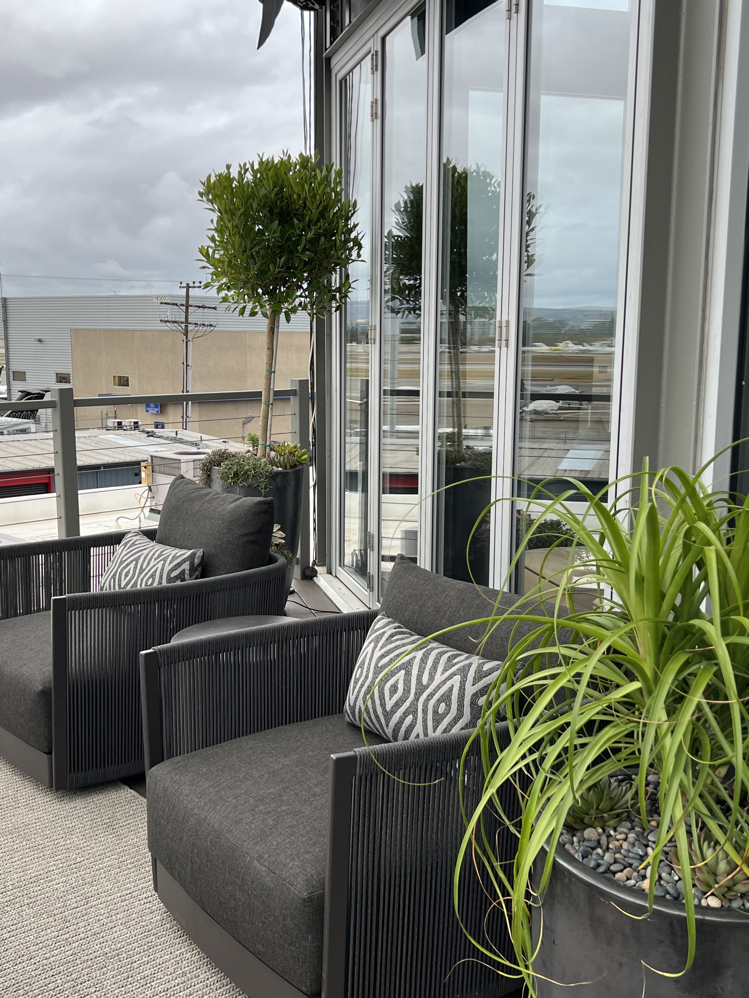 Contemporary terrace chairs and potted plants outside executive office with glass doors