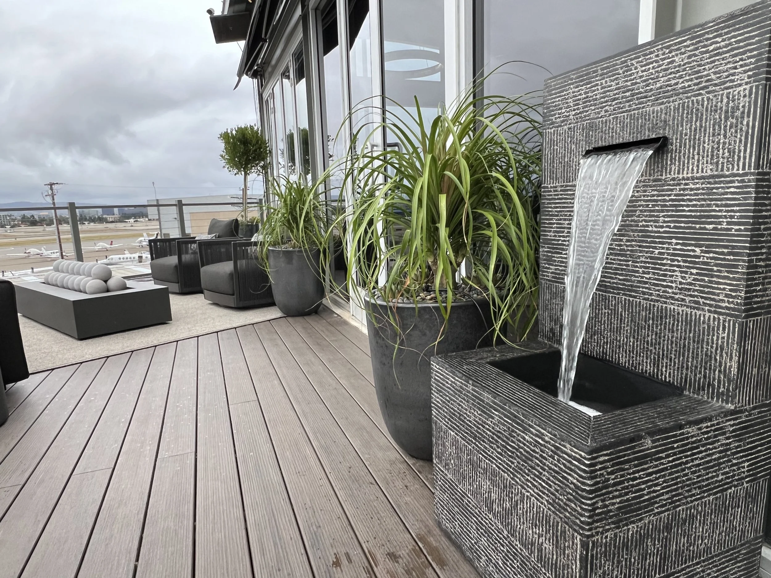 Outdoor water fountain and greenery on luxury terrace with runway views and modern decor
